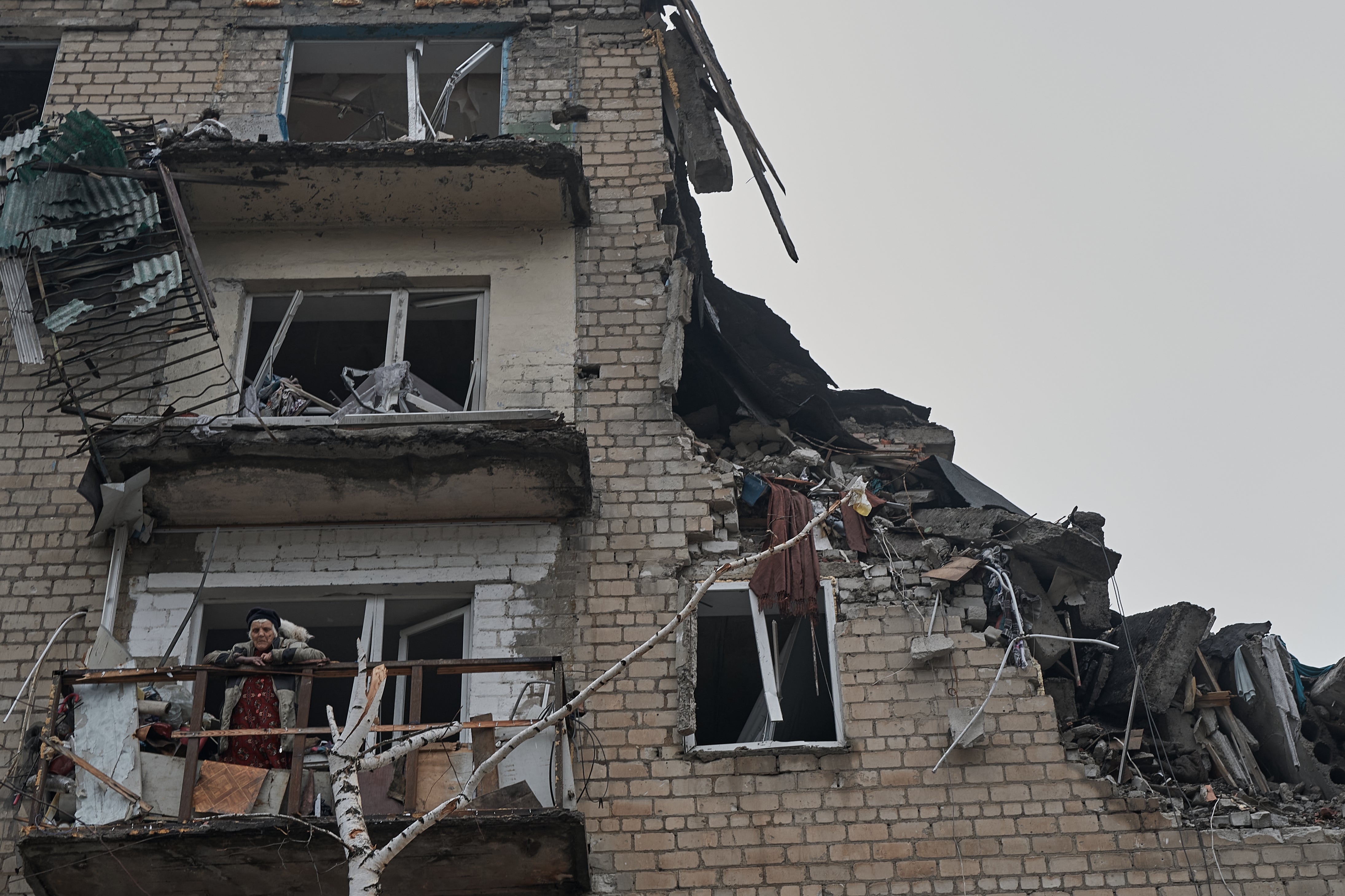 <p> An elderly civilian woman stands with a cat on the balcony of her destroyed house in the city of Avdiivka</p>