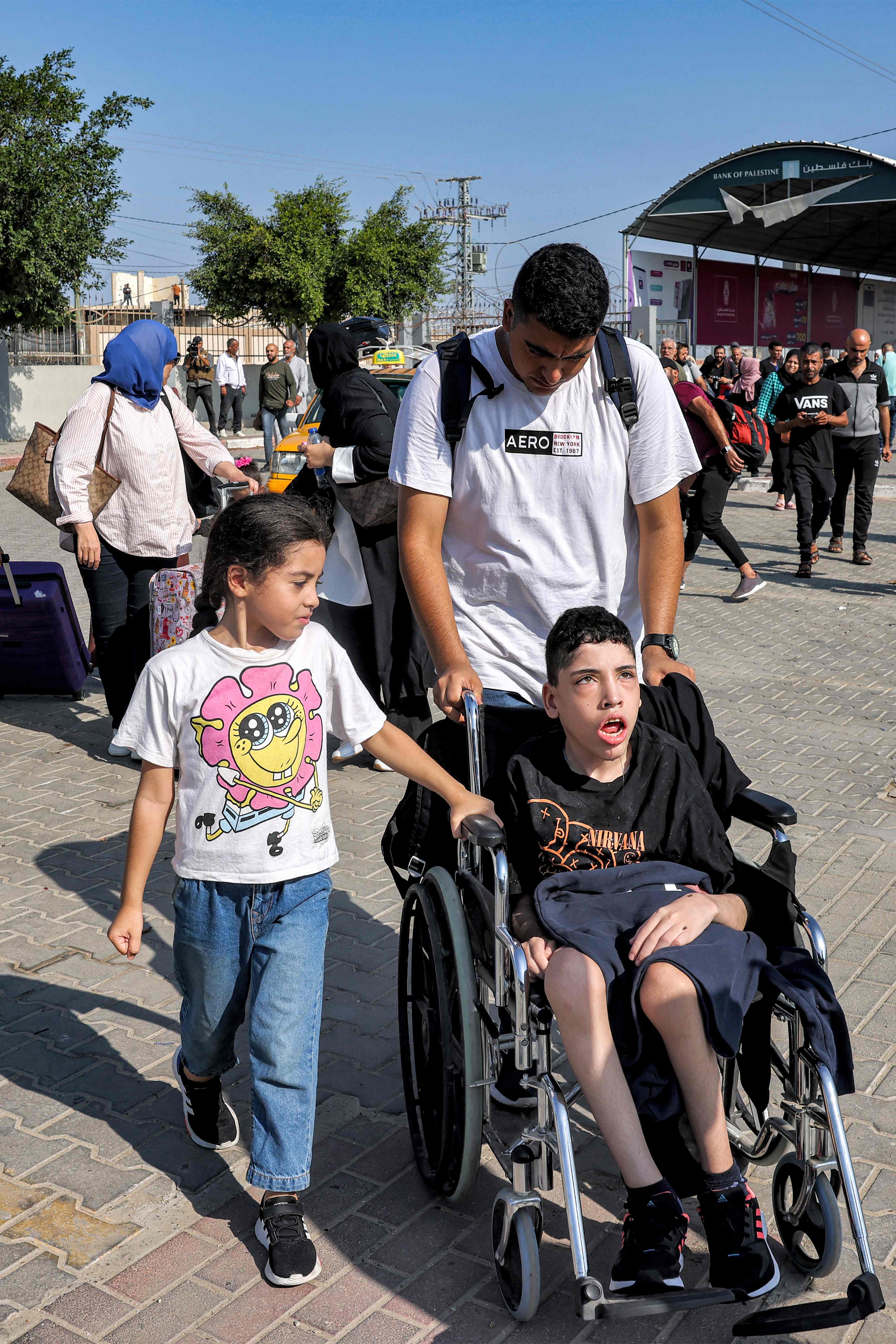 <p>A man pushes a child on a wheelchair as people enter the Rafah border crossing </p>