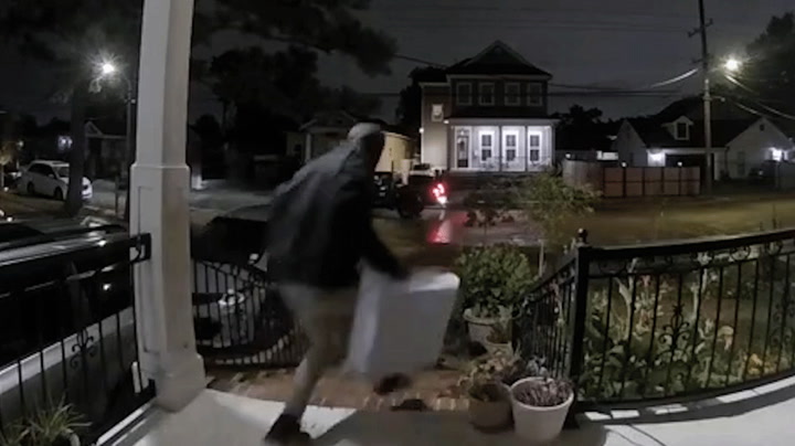 A person believed to be a 'porch pirate' takes a package immediately after a UPS truck leaves the area.