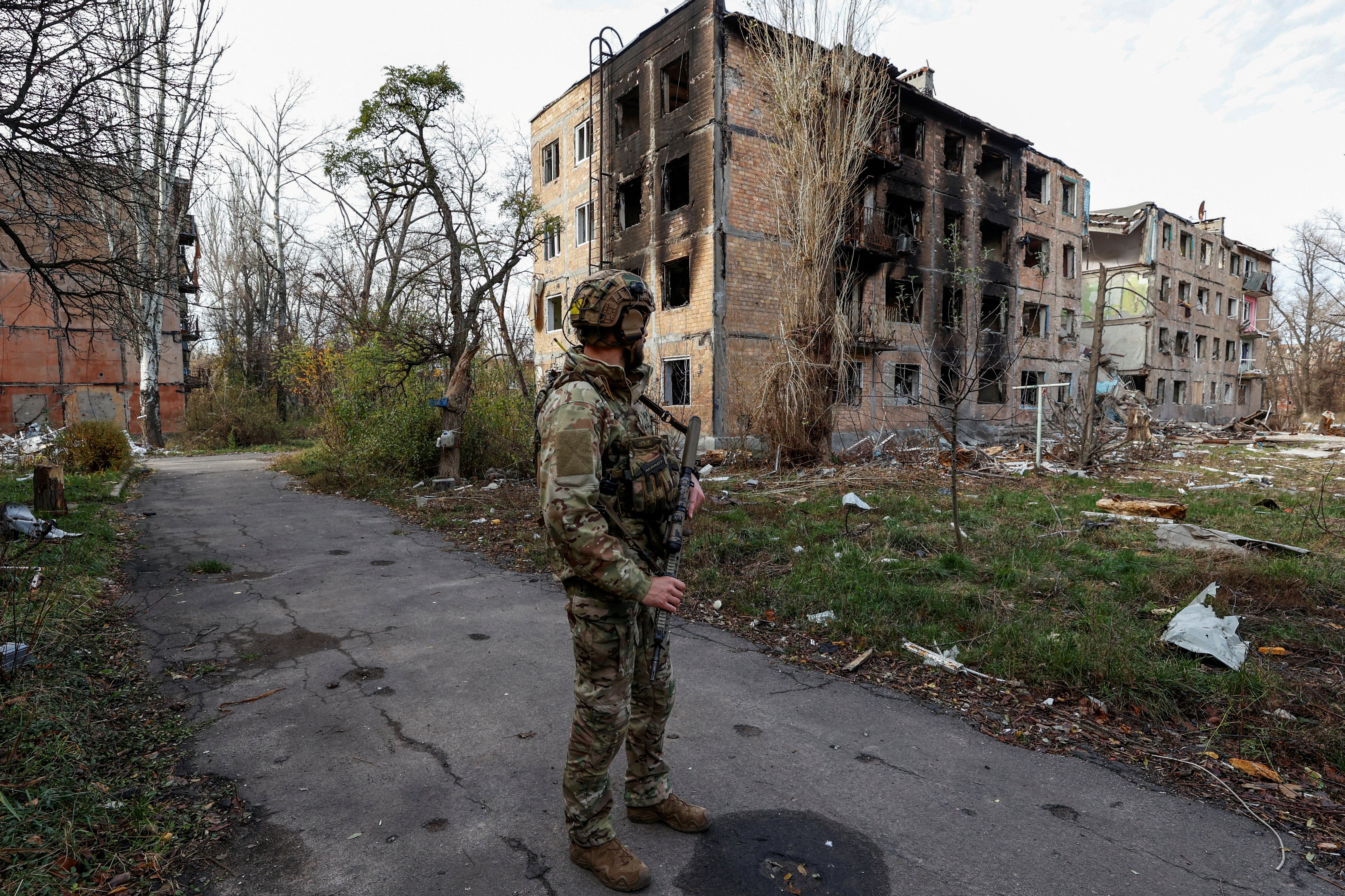 <p>A Ukrainian serviceman stands next to residential buildings heavily damaged by permanent Russian military strikes in the front line town of Avdiivka</p>