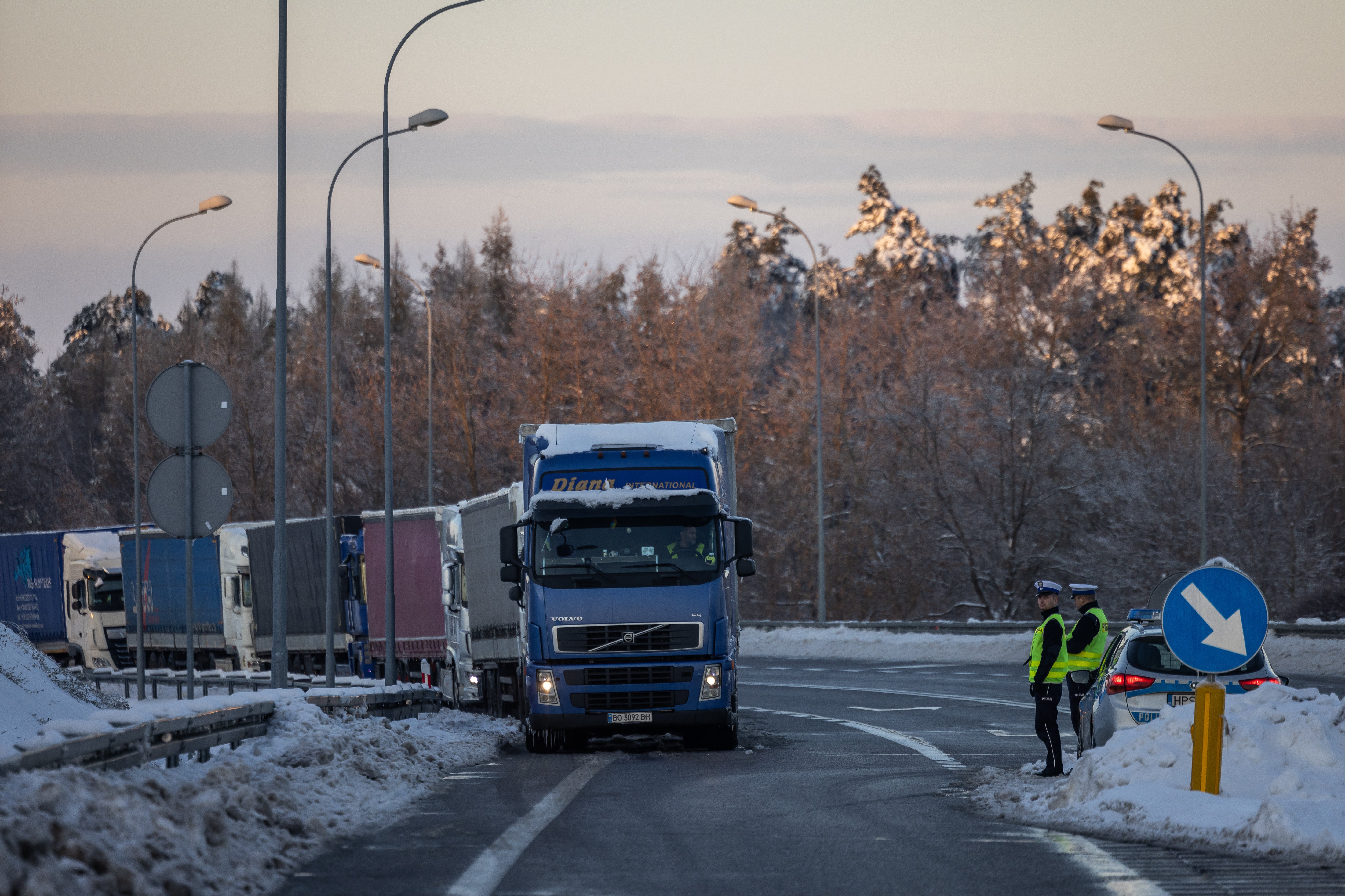 <p>Police officers stand as trucks belonging to different Polish transport company owners block the access to Polish-Ukraine border crossing in protest against ‘unfair' competition in Hrebenne, Poland</p>