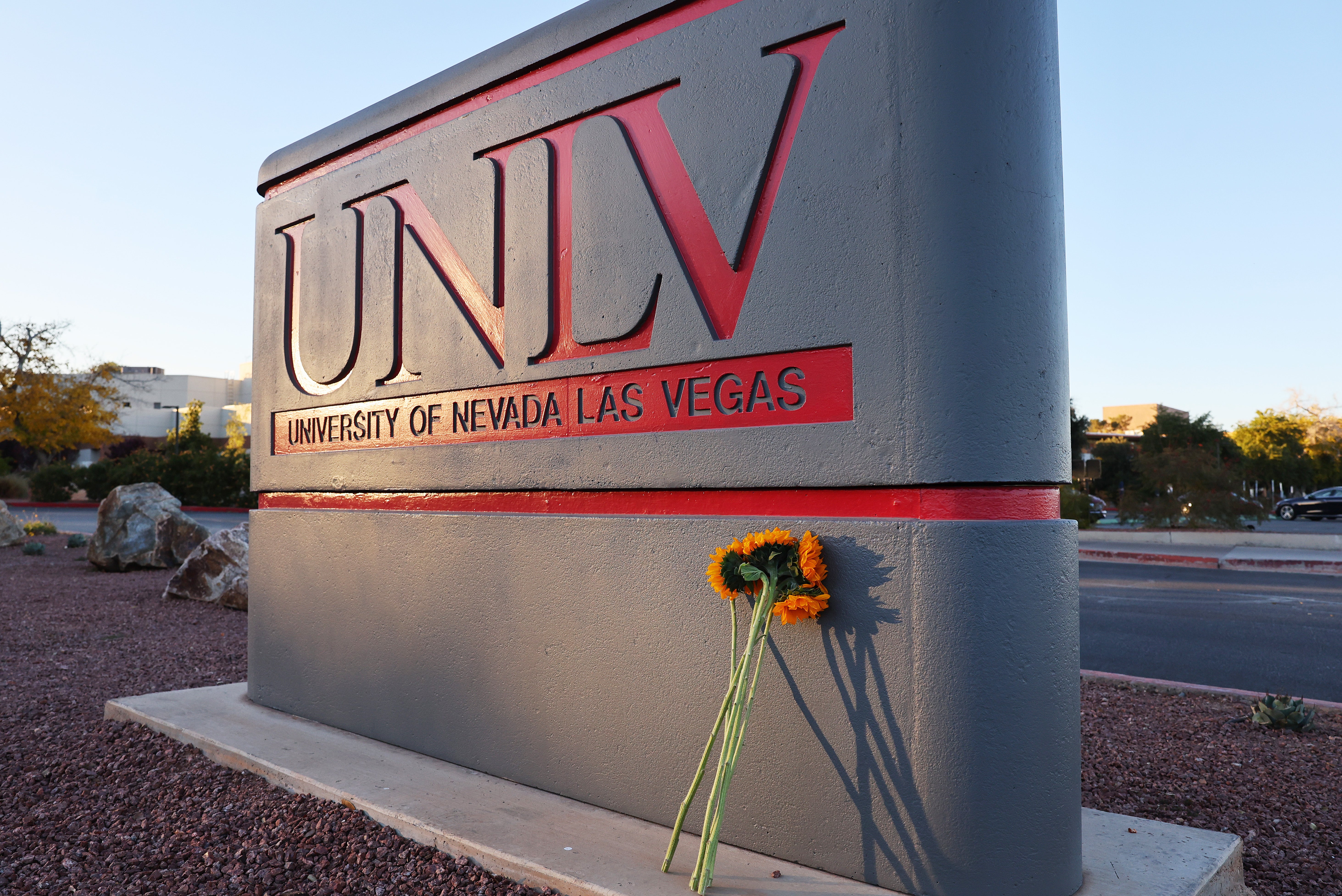 <p>Flowers rest against a UNLV campus sign after a December 6 shooting left three dead</p>