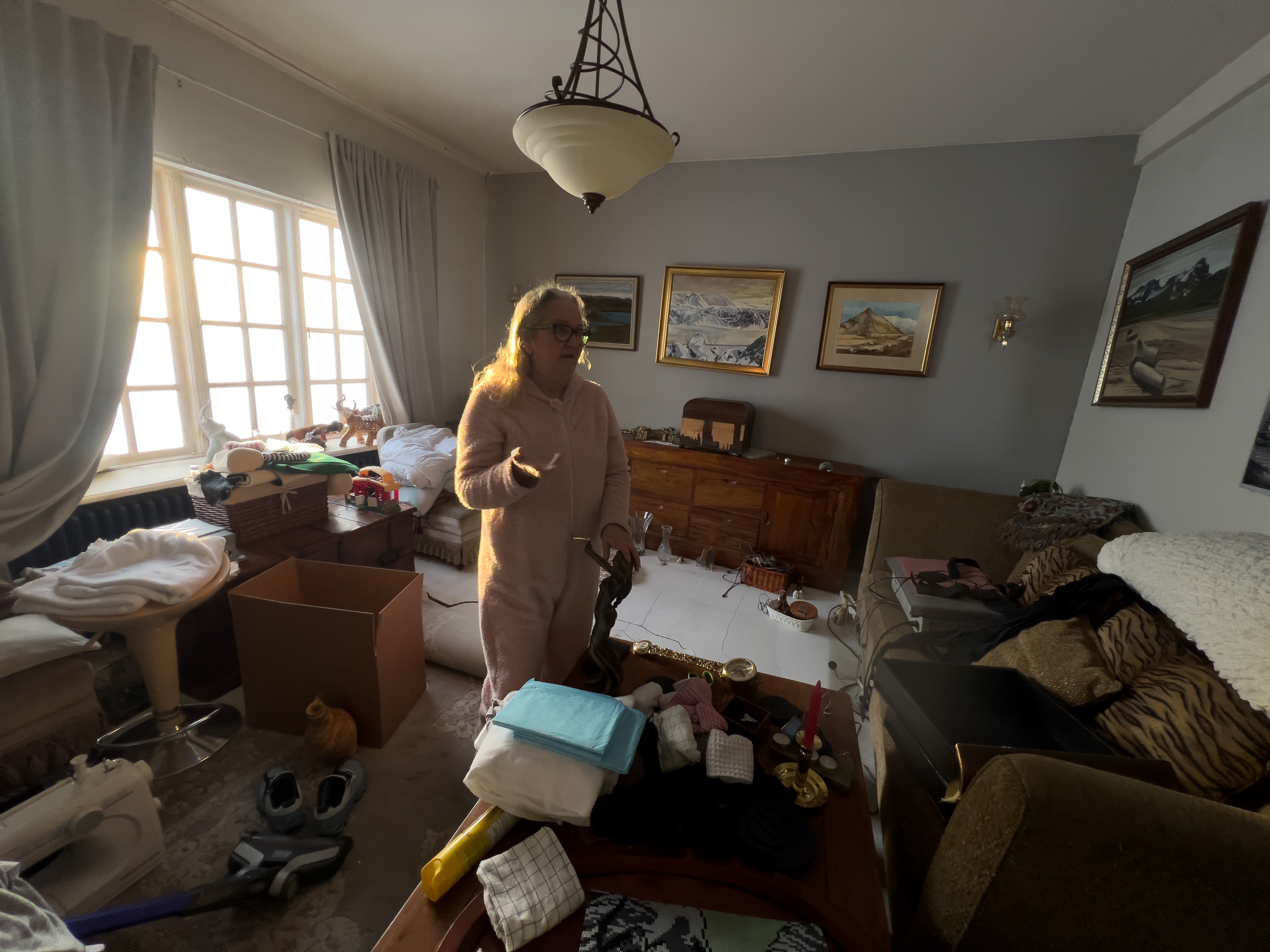 <p>A resident in her living room of a house sitting on fault line damaged by earthquakes in Grindavik sorting through her possessions</p>