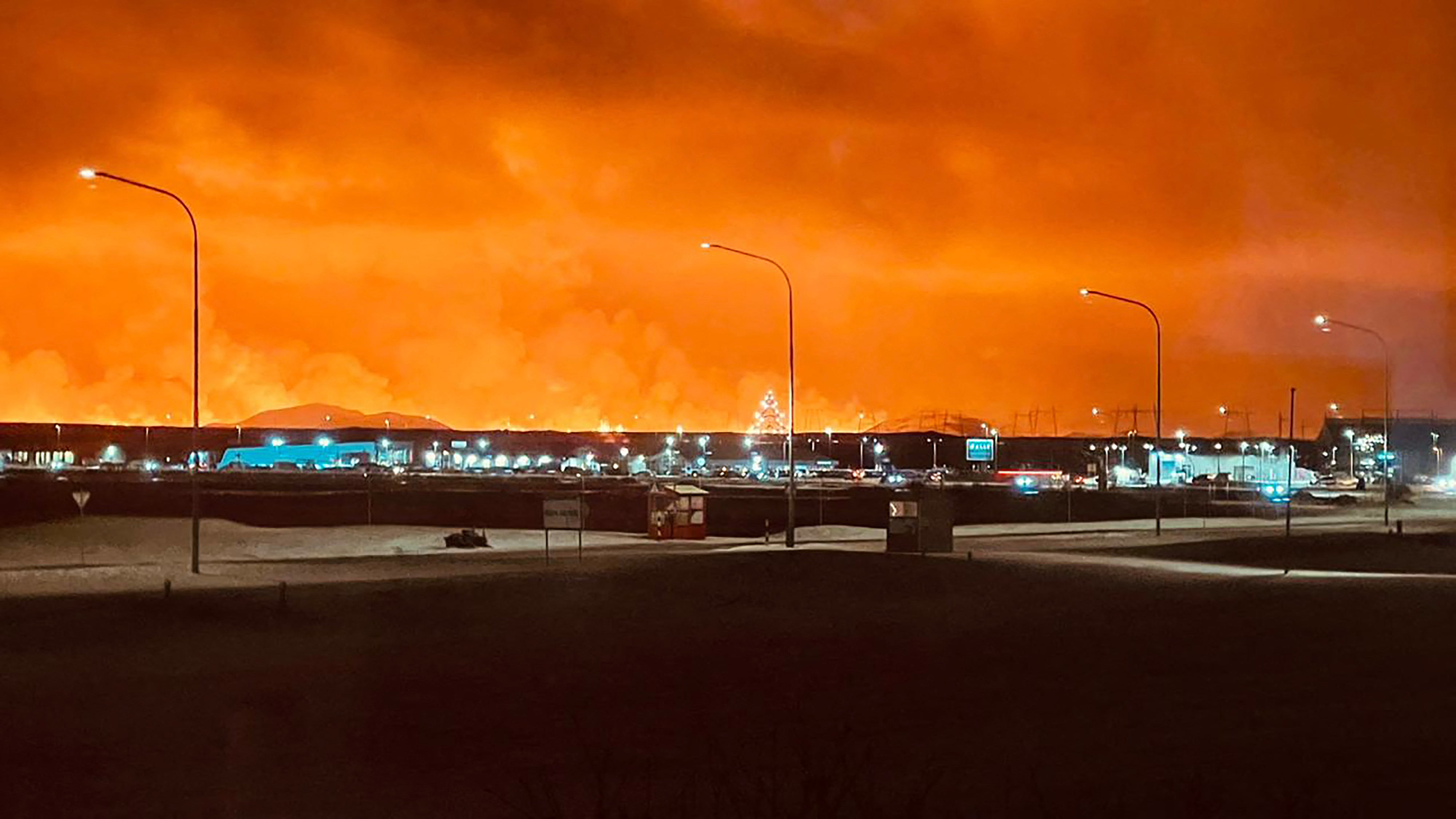 <p>Roads in the town of Keflavik are pictured as smoke billow with lava colouring the night sky orange from an volcanic eruption on the Reykjanes peninsula</p>