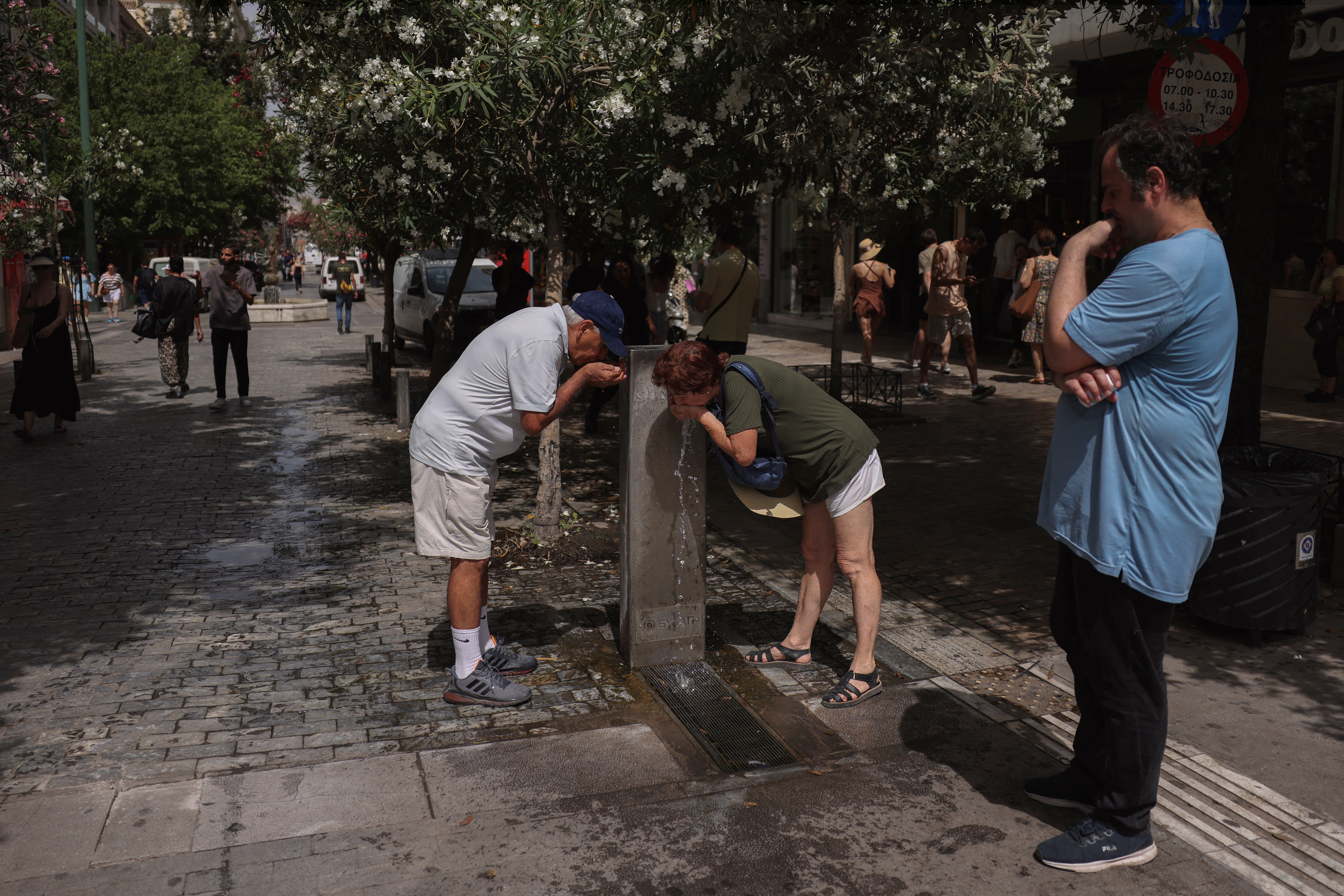 People drinking from water fountains in intense heat in Greece