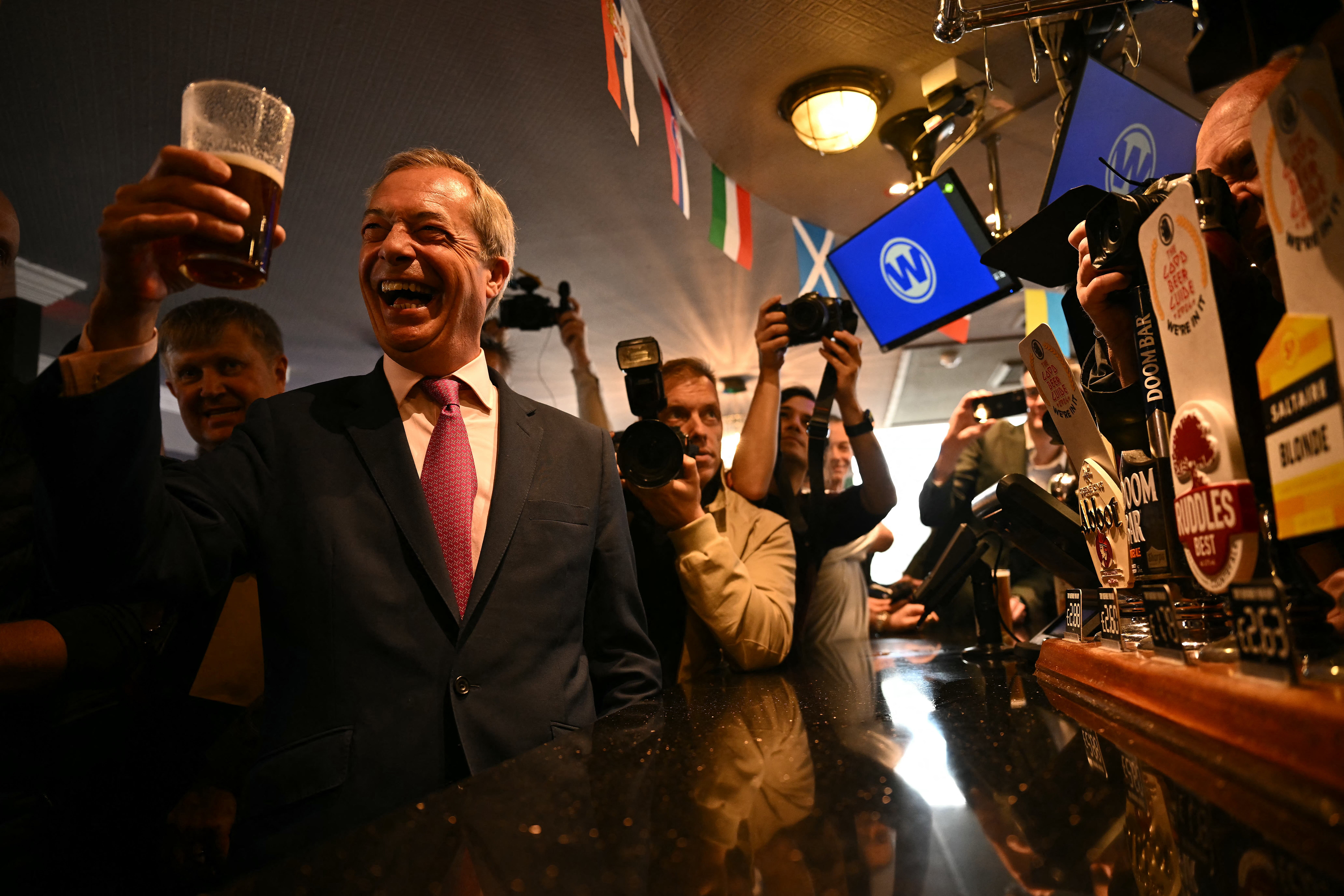 Newly appointed leader of Britain's right-wing populist party, Reform UK, and the party's parliamentary candidate for Clacton, Nigel Farage, poses with a pint of beer in a Wetherspoons pub