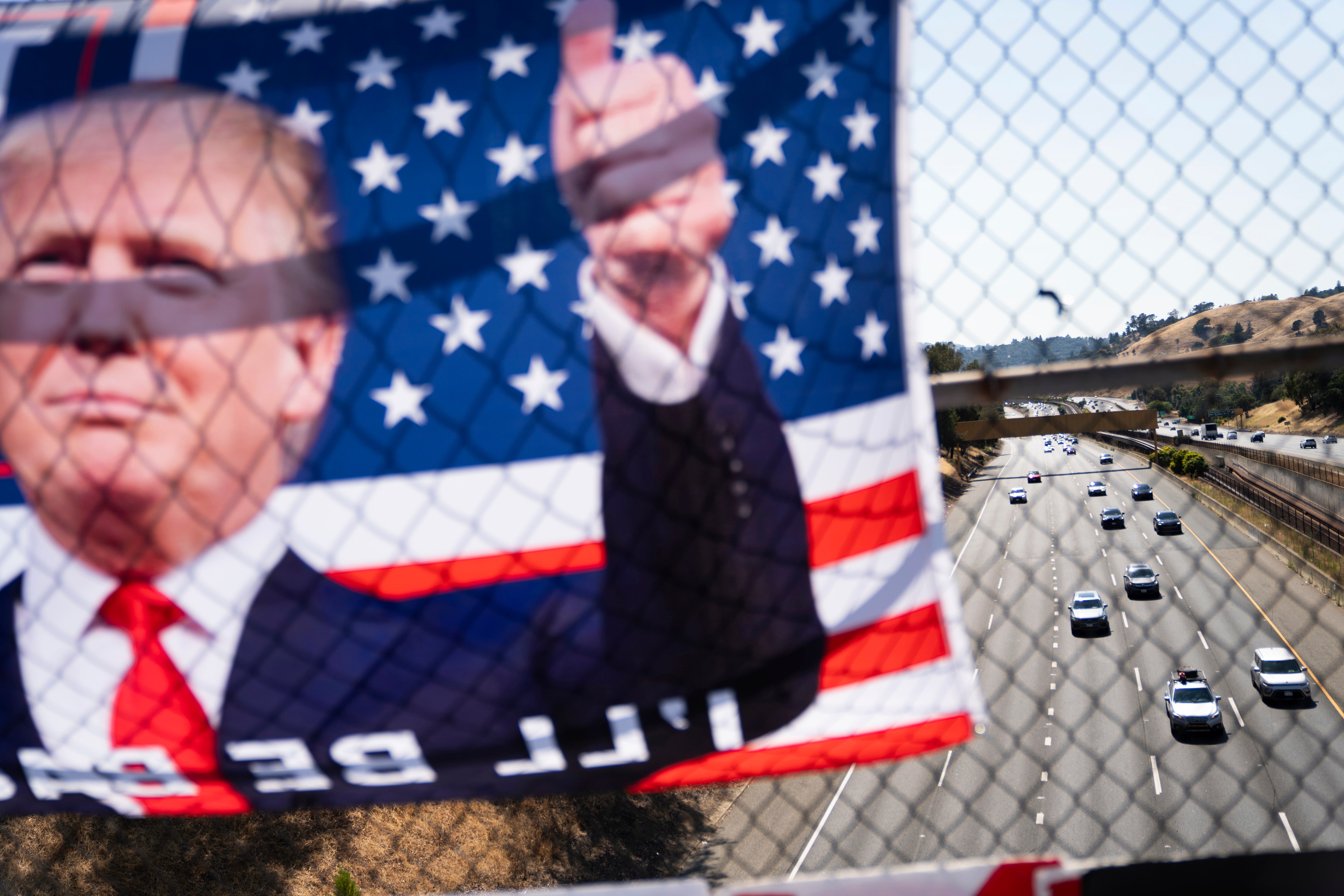 A flag displaying Republican presidential candidate former president Donald Trump hangs over a Highway 24 overpass in Lafayette, California on Sunday, 14 July 2024