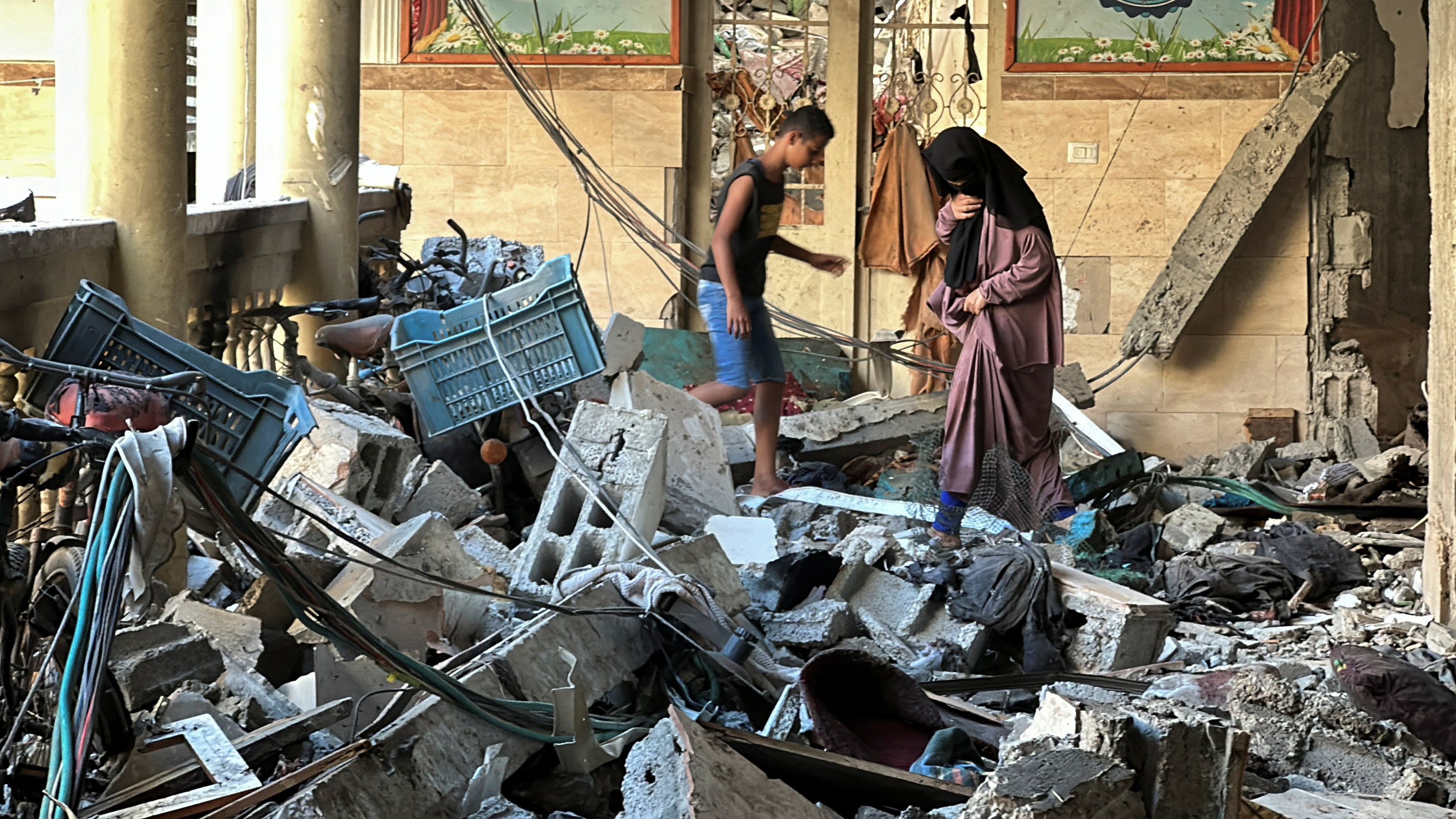 Palestinians inspect the site of an Israeli strike on a school sheltering displaced people