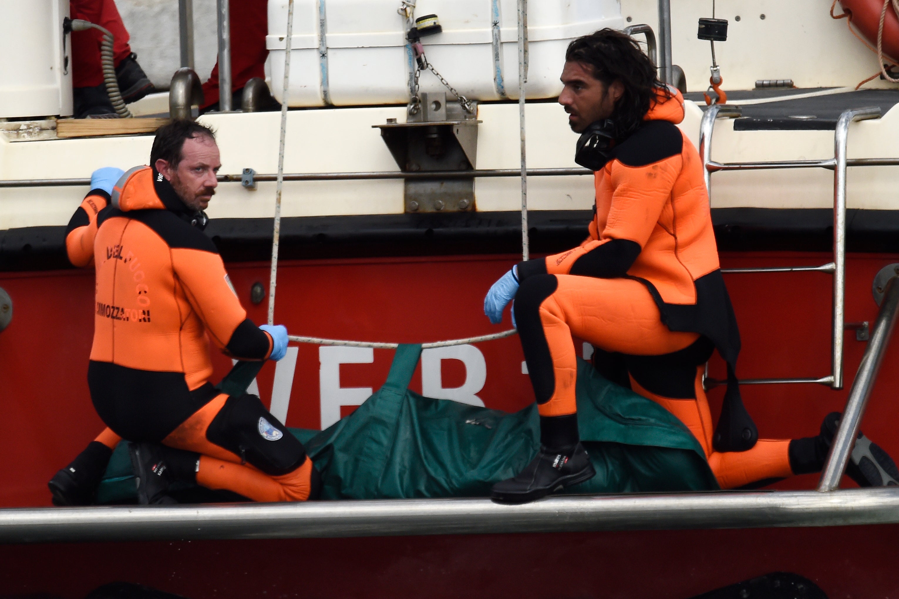 Italian firefighter scuba divers bring ashore, in the green bag, the body of one of the victims from the British-flagged vessel Bayesian