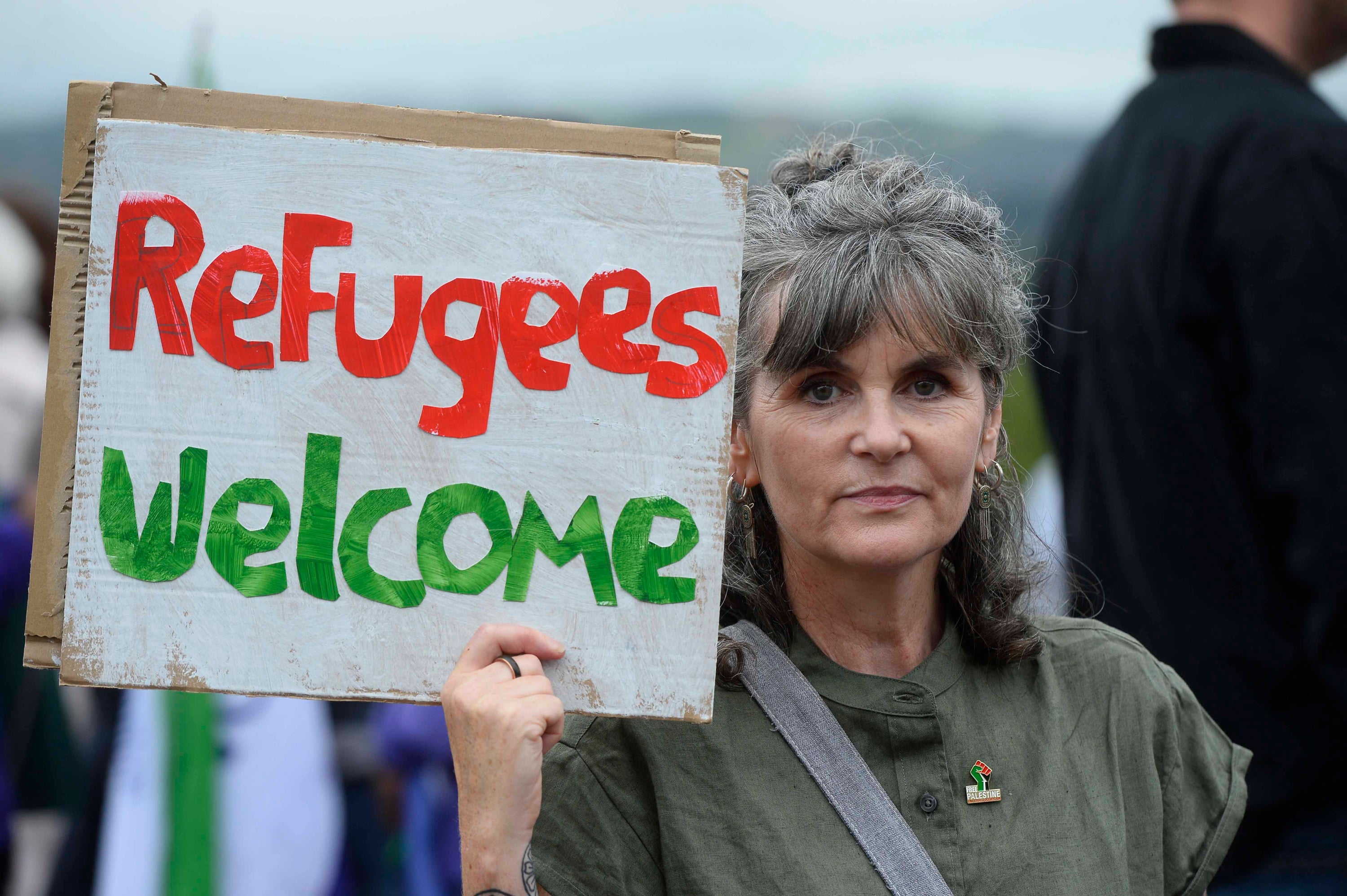 A woman holds a ‘Refugees welcome’ placard at a demonstration outside Northern Ireland’s parliament