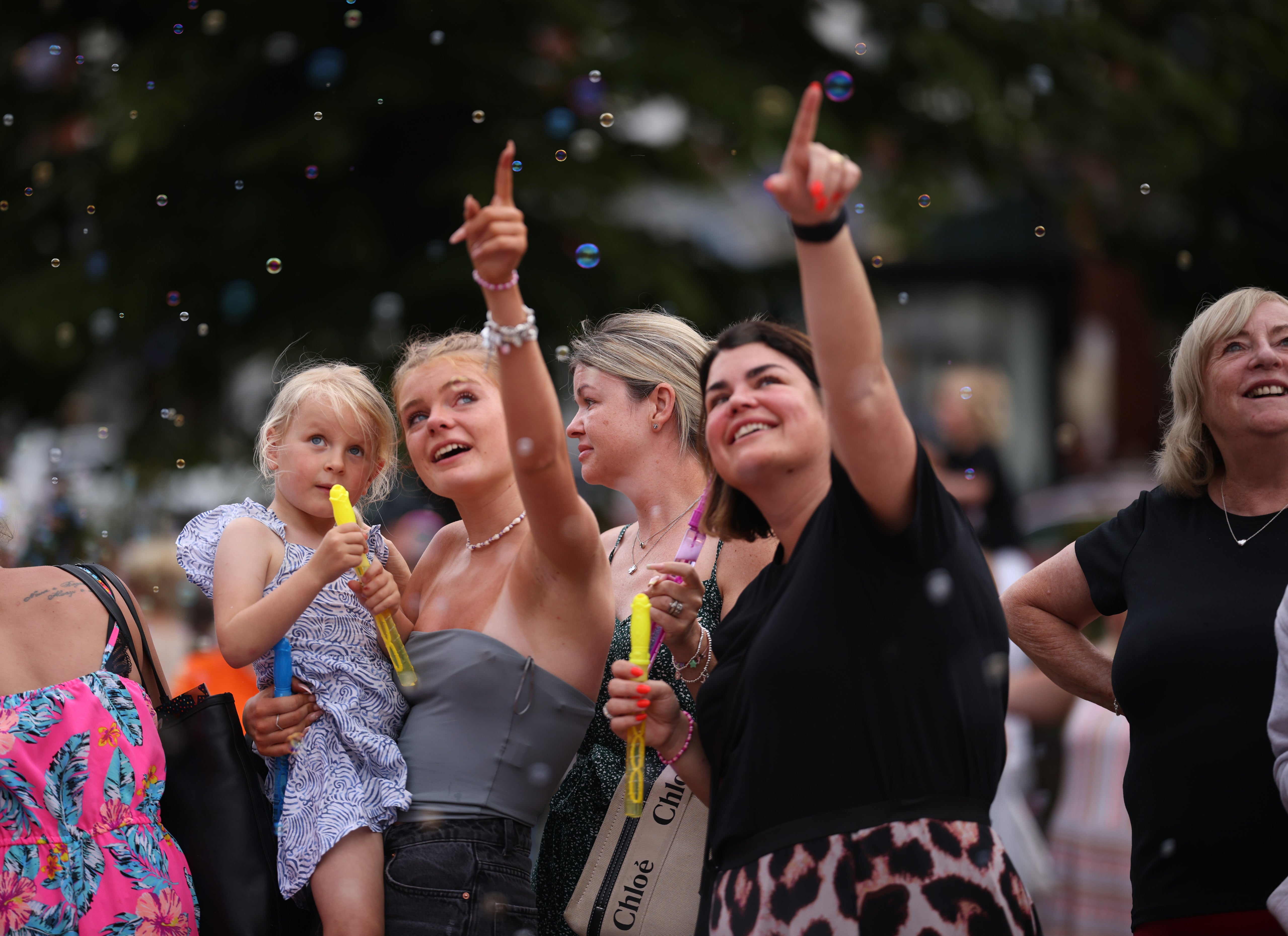 Adults and children blow bubbles as they gather to mourn victims of last week's knife attack in Southport