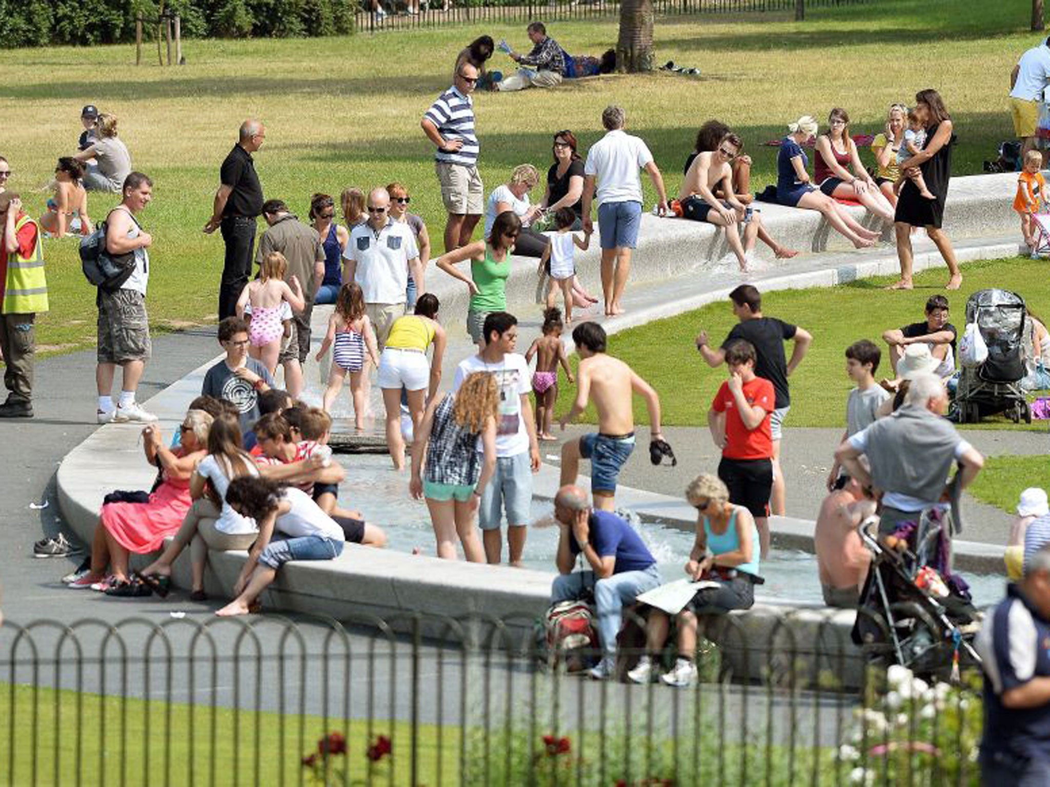 People cool off in the Diana, Princess of Wales Memorial Fountain in Hyde Park