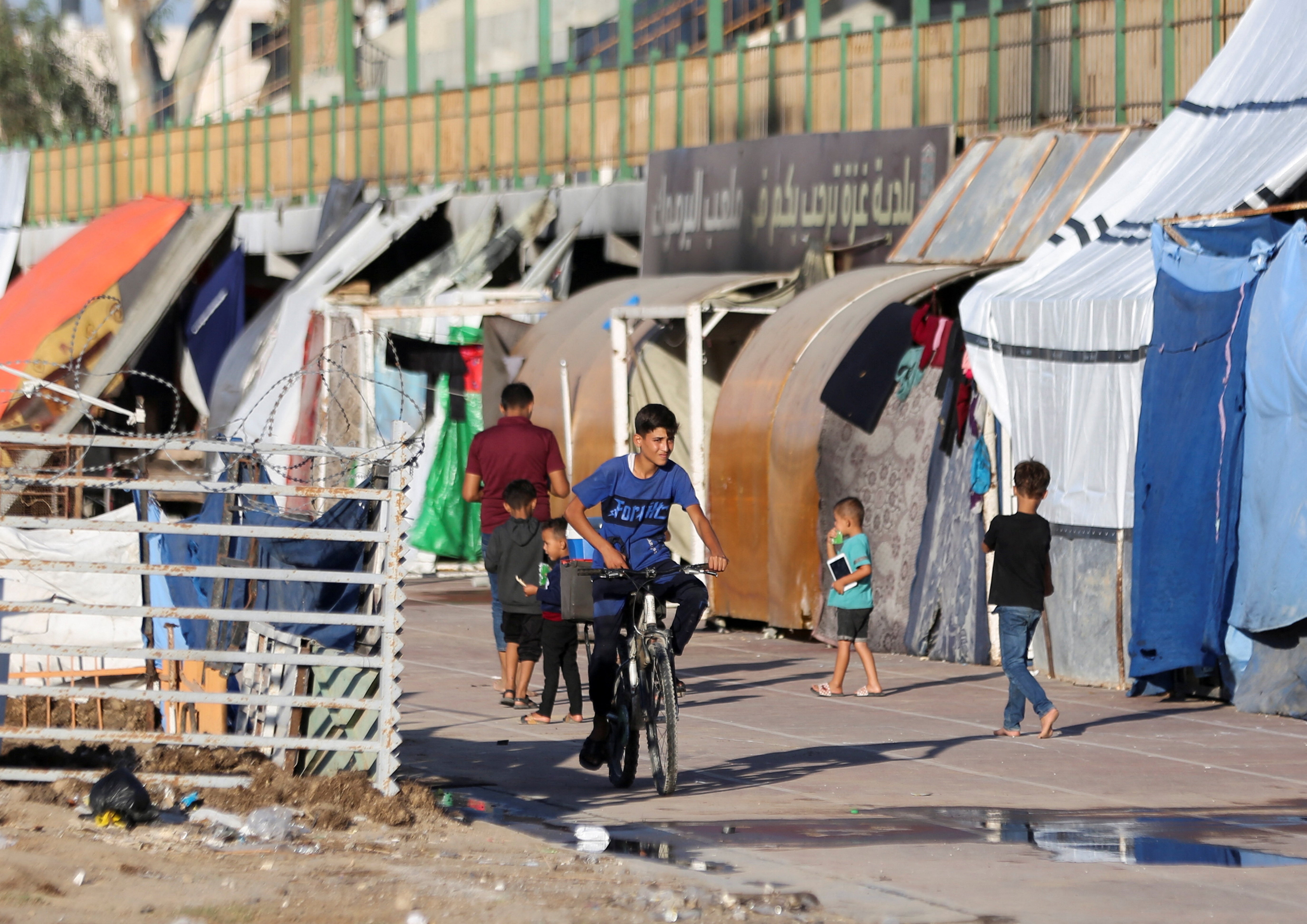 A boy rides a bike as displaced Palestinians take shelter in a stadium