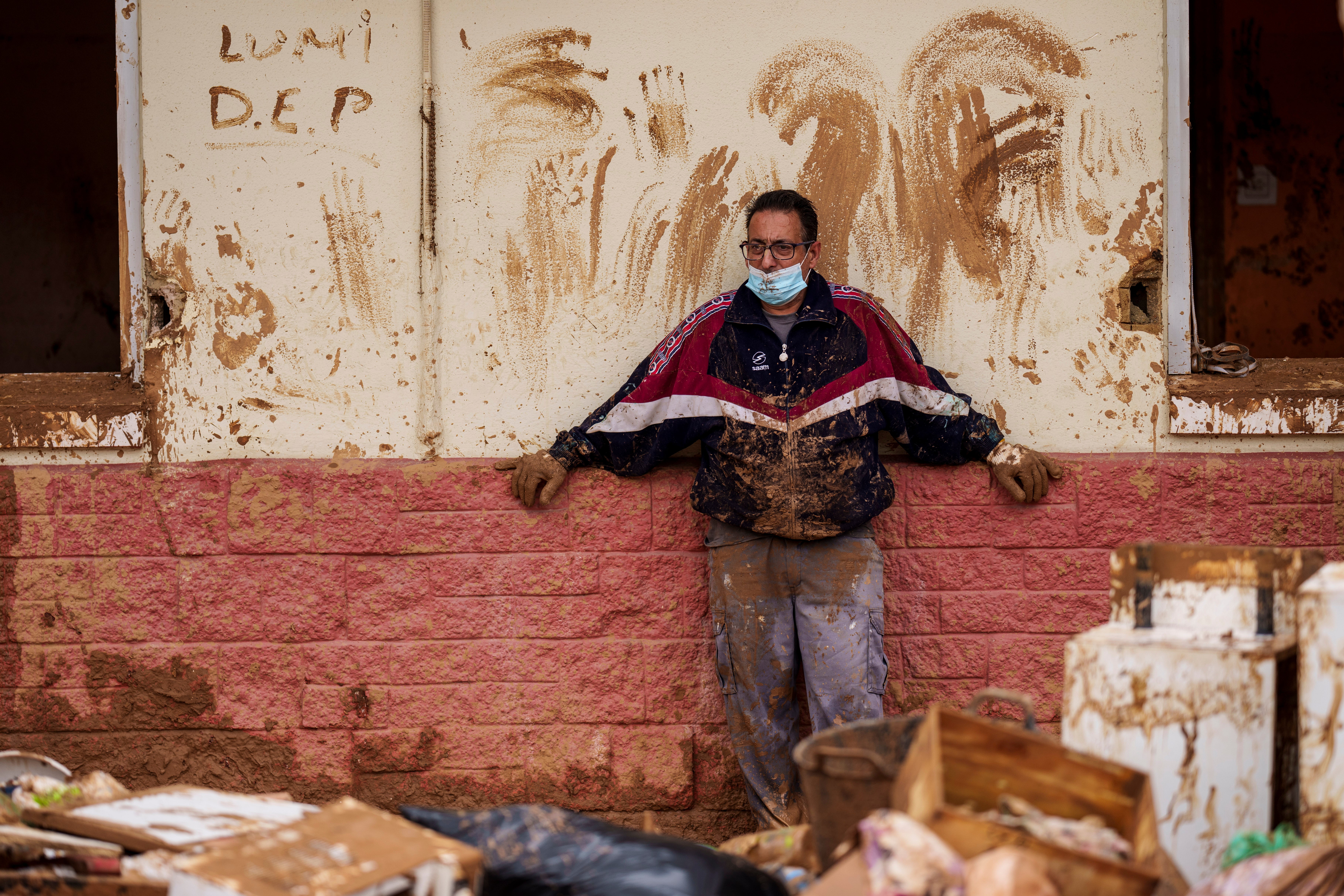 A man looks at the damage and debris in front of a house a affected by floods in Alfafar, Spain