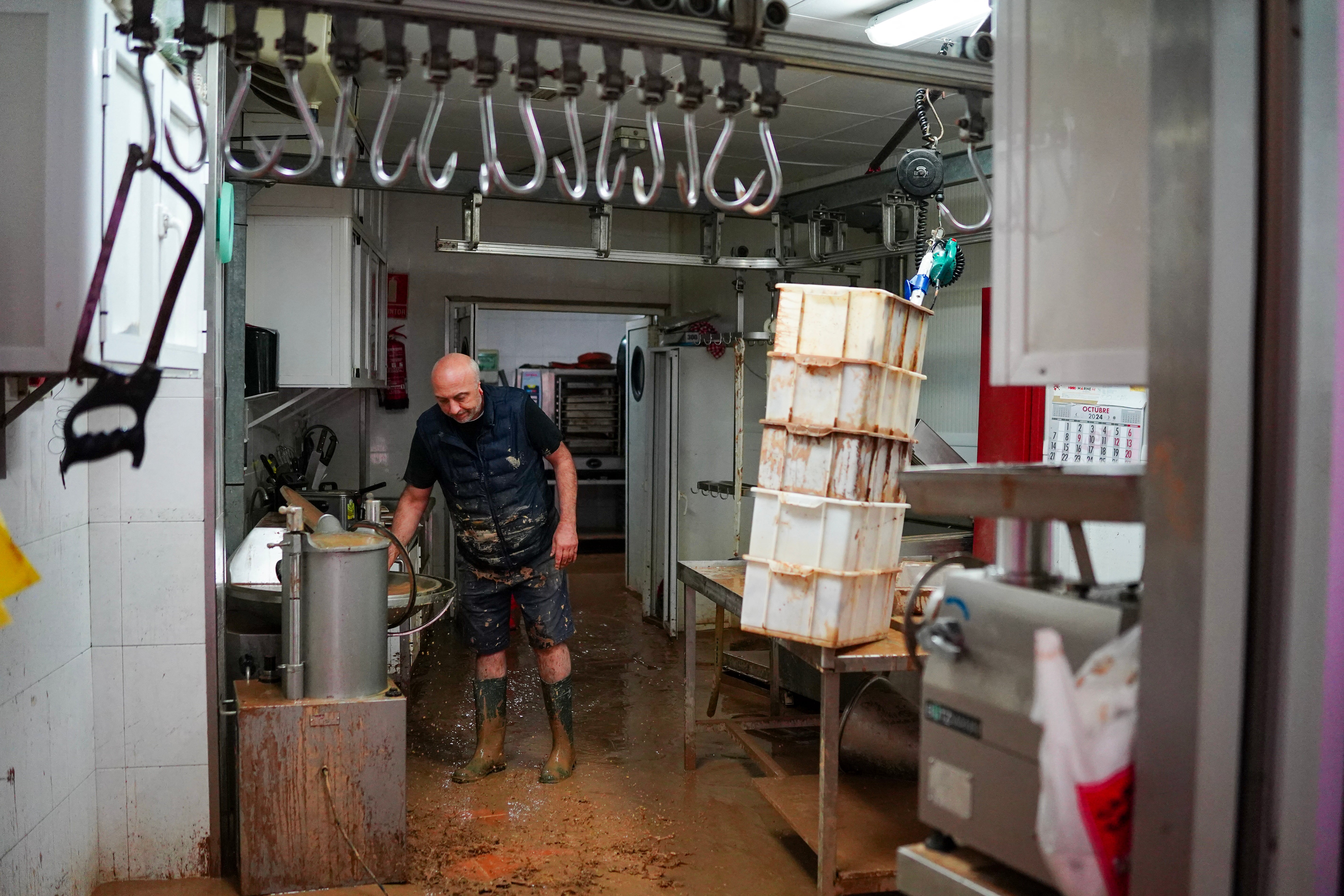 Butcher clears mud from his shop on Saturday morning