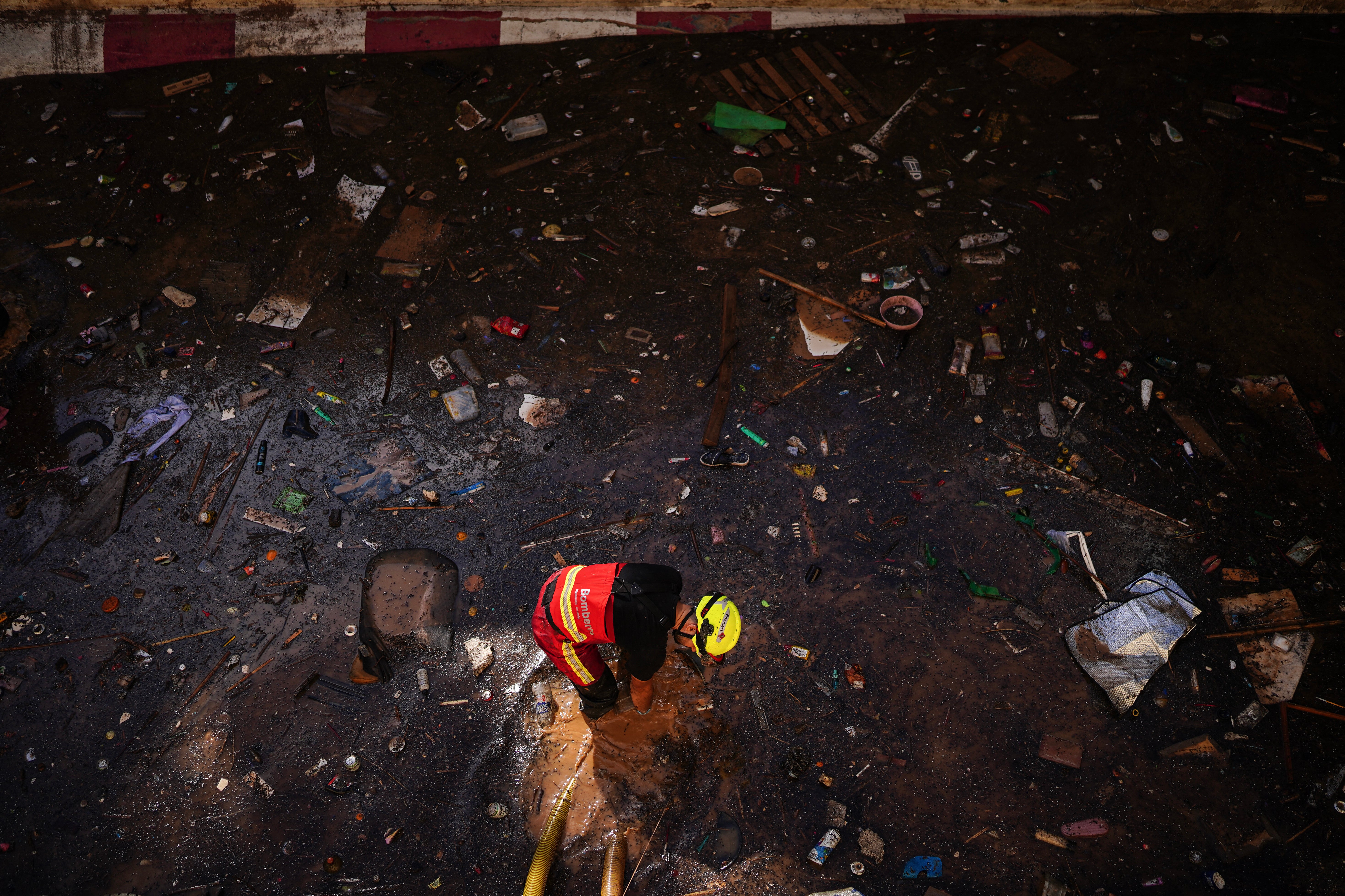 A firefighter clears water from an underpass in the search for bodies amongst the debris