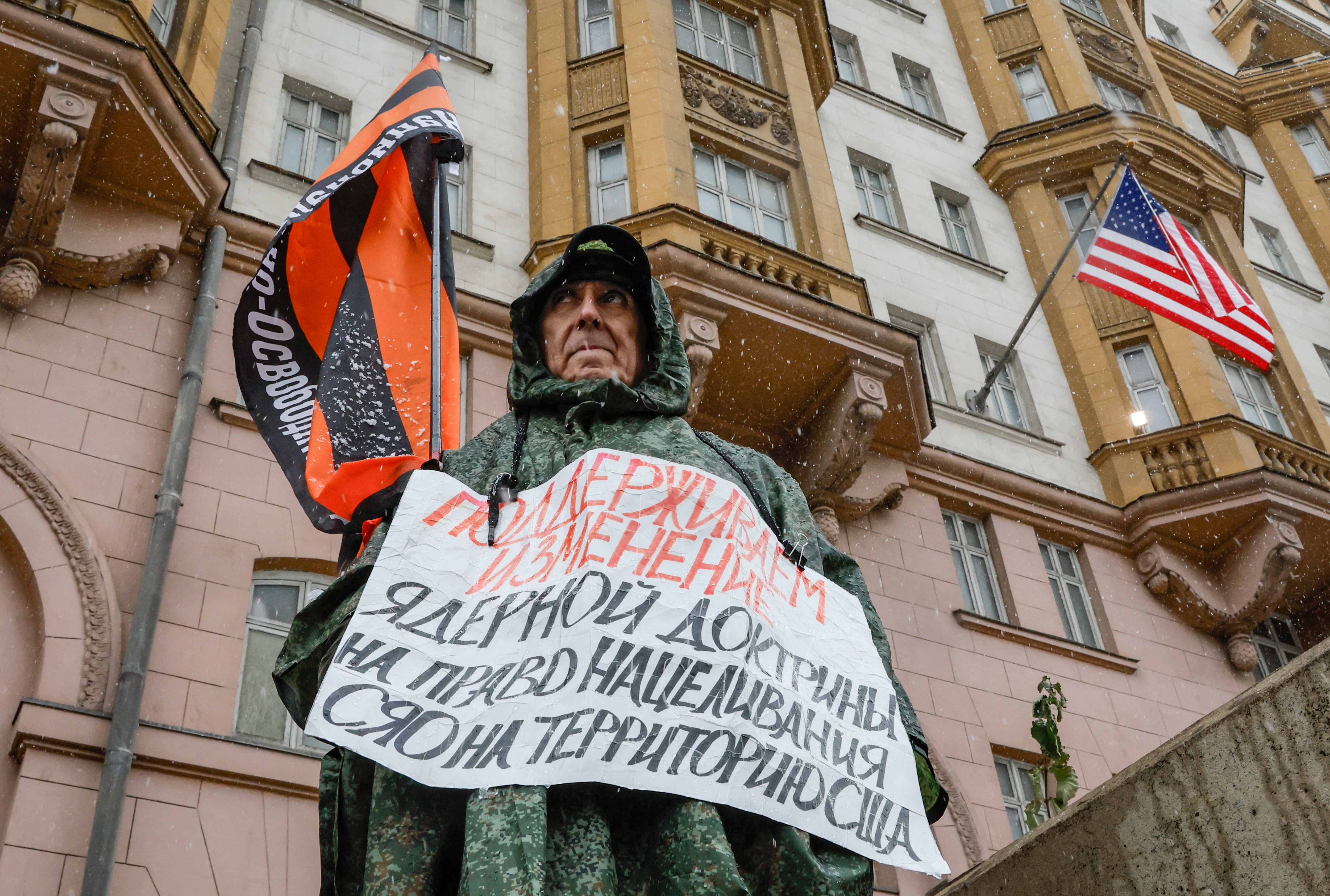 A man with a flag carrying the name of the organization 'National Liberation Movement', and a poster reading 'We support changing the nuclear doctrine to allow for the right to target strategic nuclear weapons at US territory', participates in a single picket against the US policy in Ukraine, near the US embassy in Moscow, Russia