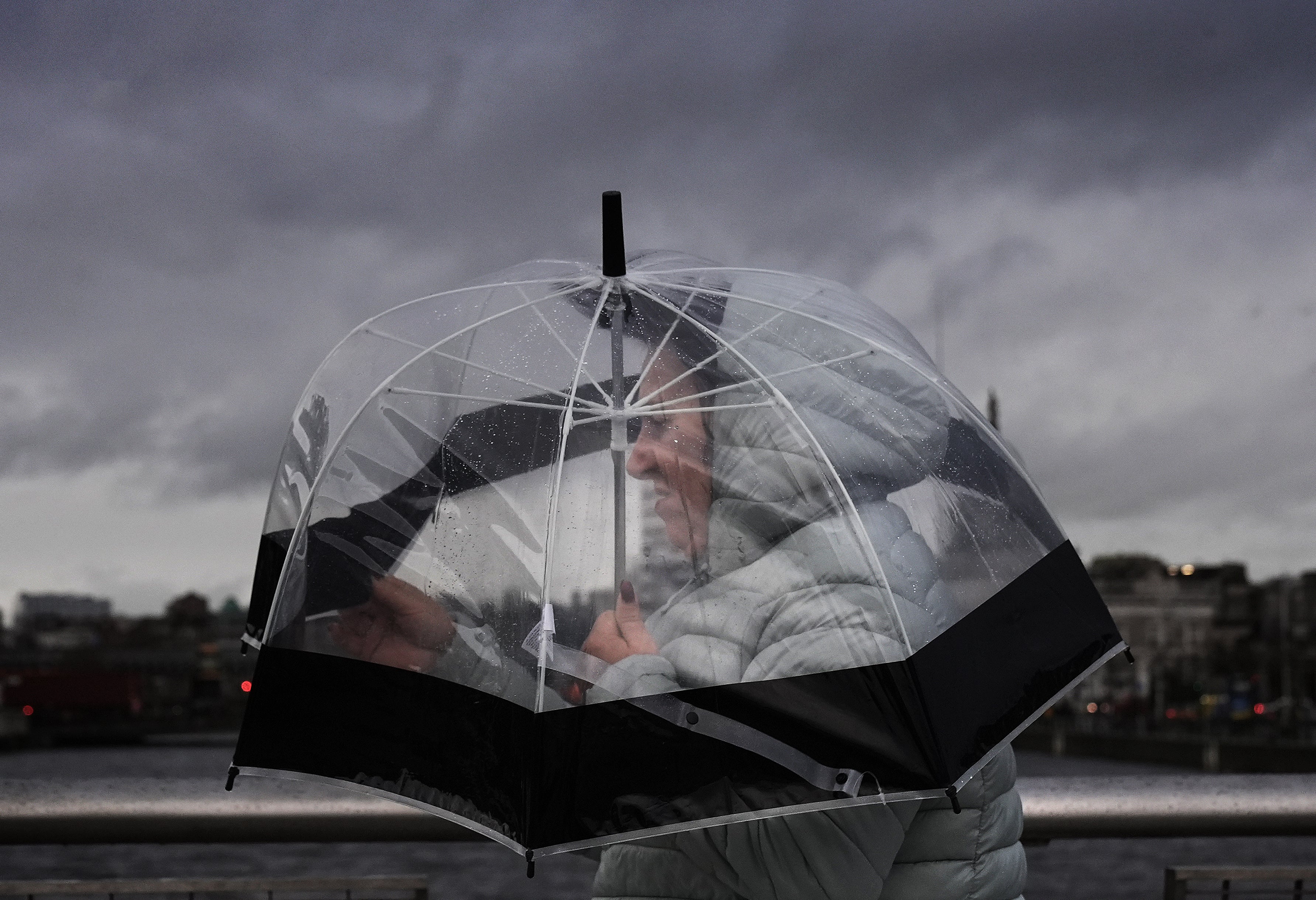 A person takes shelter under an umbrella as they cross the Sean O'Casey Bridge in Dublin's city centre