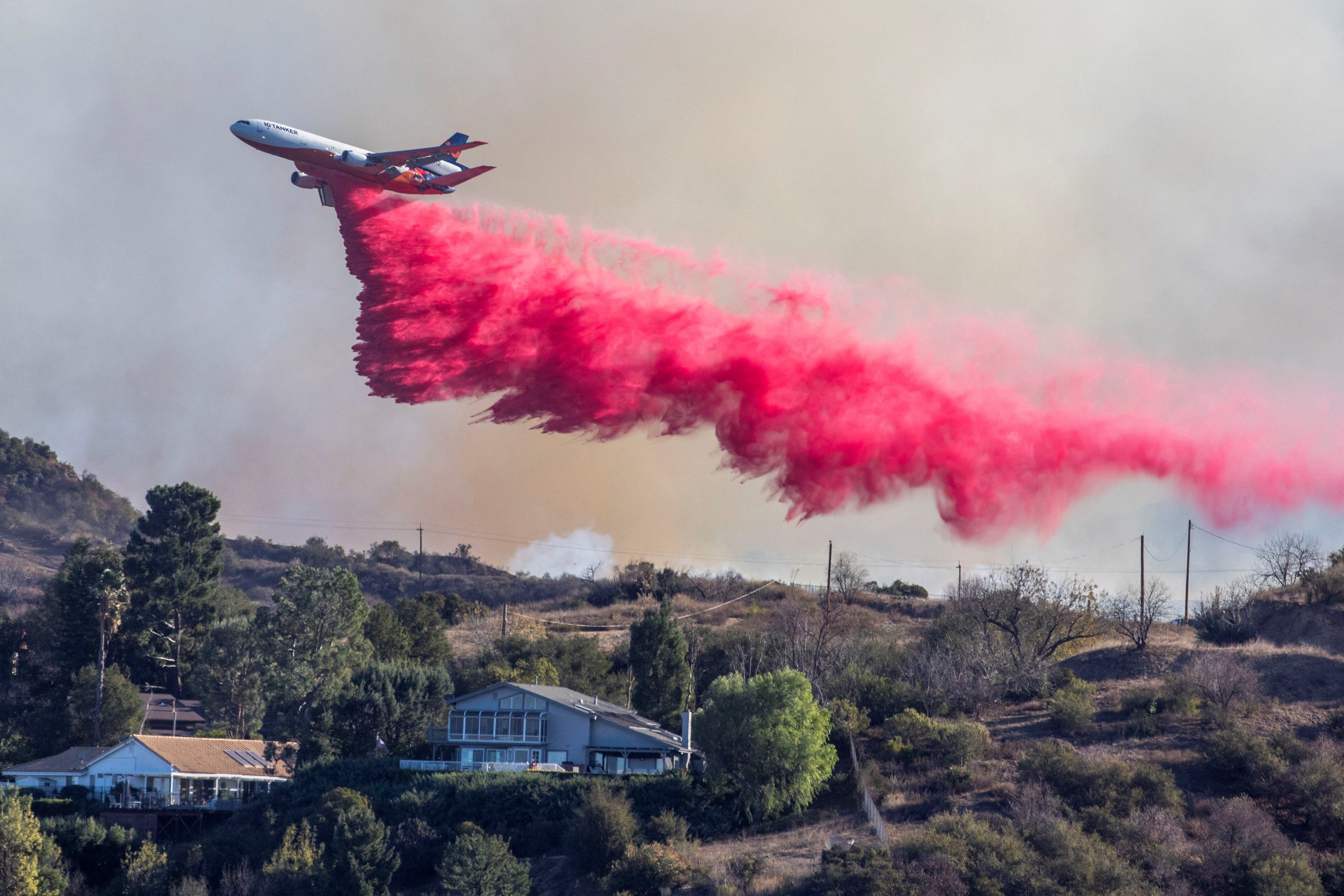 An air tanker drops fire retardant at the Palisades Fire, one of simultaneous blazes that have ripped across Los Angeles County