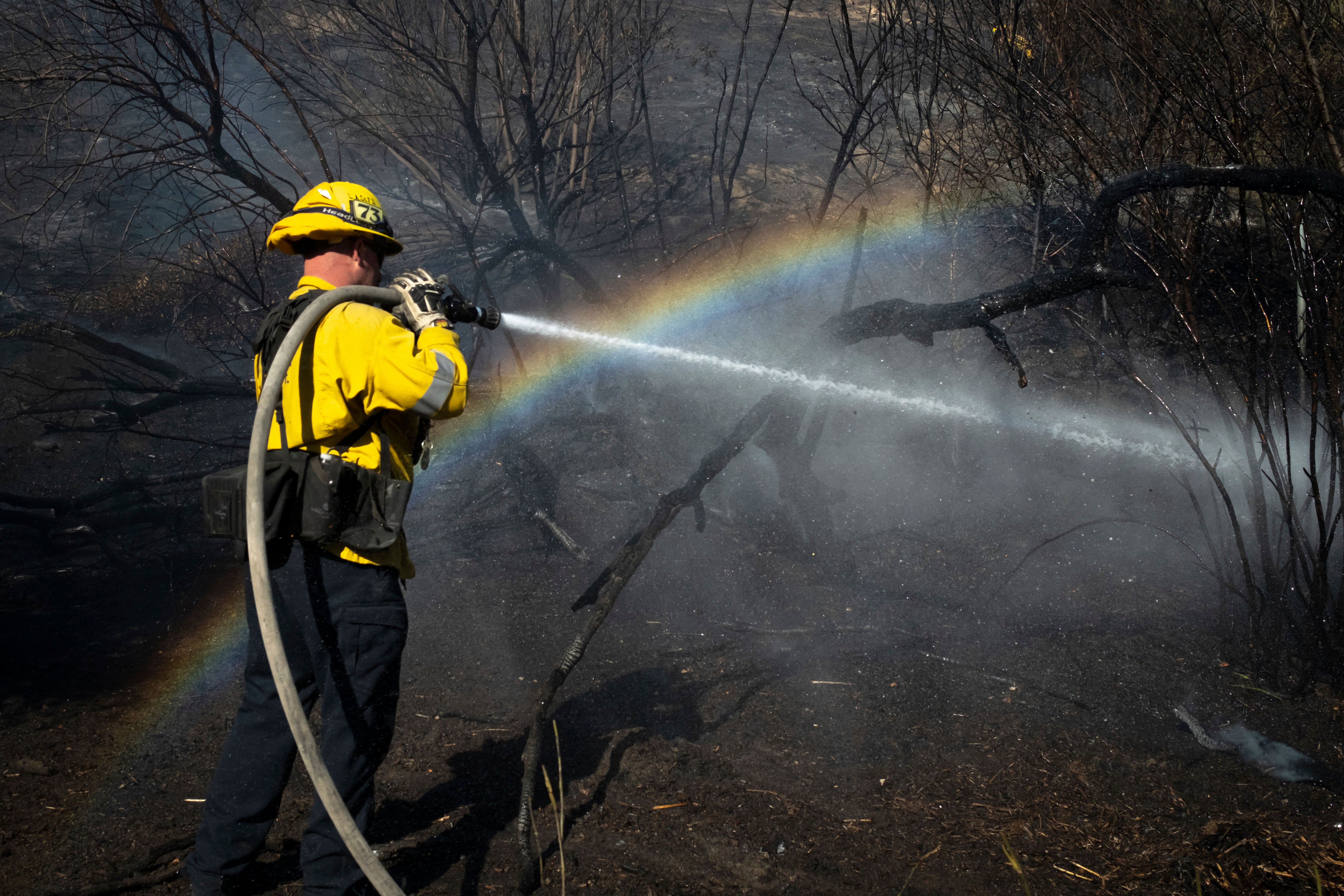 A firefighter hoses down hot spots from the Archer Fire in the Granada Hills section of Los Angeles, California, on Friday. Firefighters made progress on the large blazes as weather conditions slightly calmed