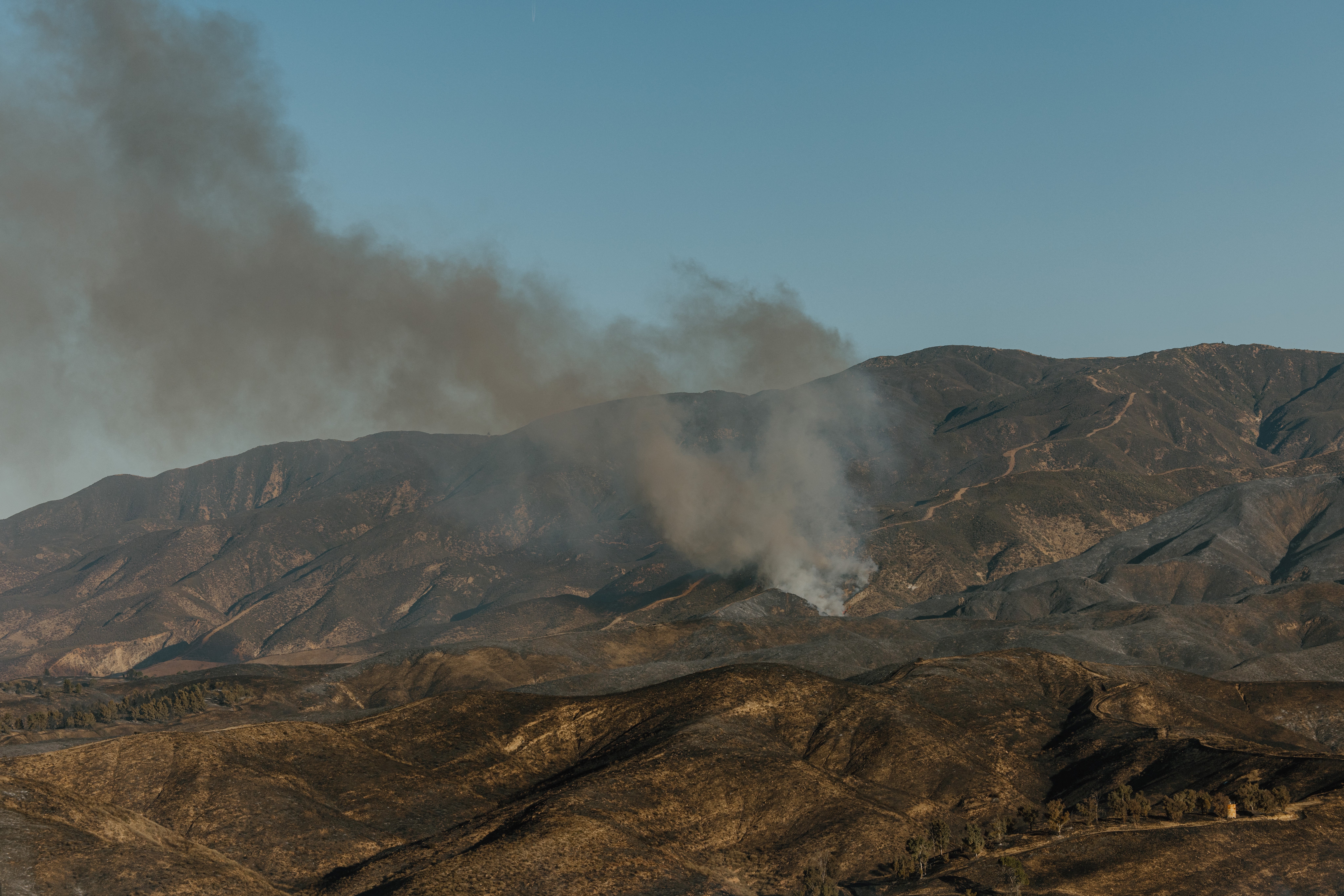 Smoke rises over the charred hills of the Angeles National Forest following the Hughes fire near Santa Clarita, California, on Thursday. More than 1,700 personnel are working on the fire