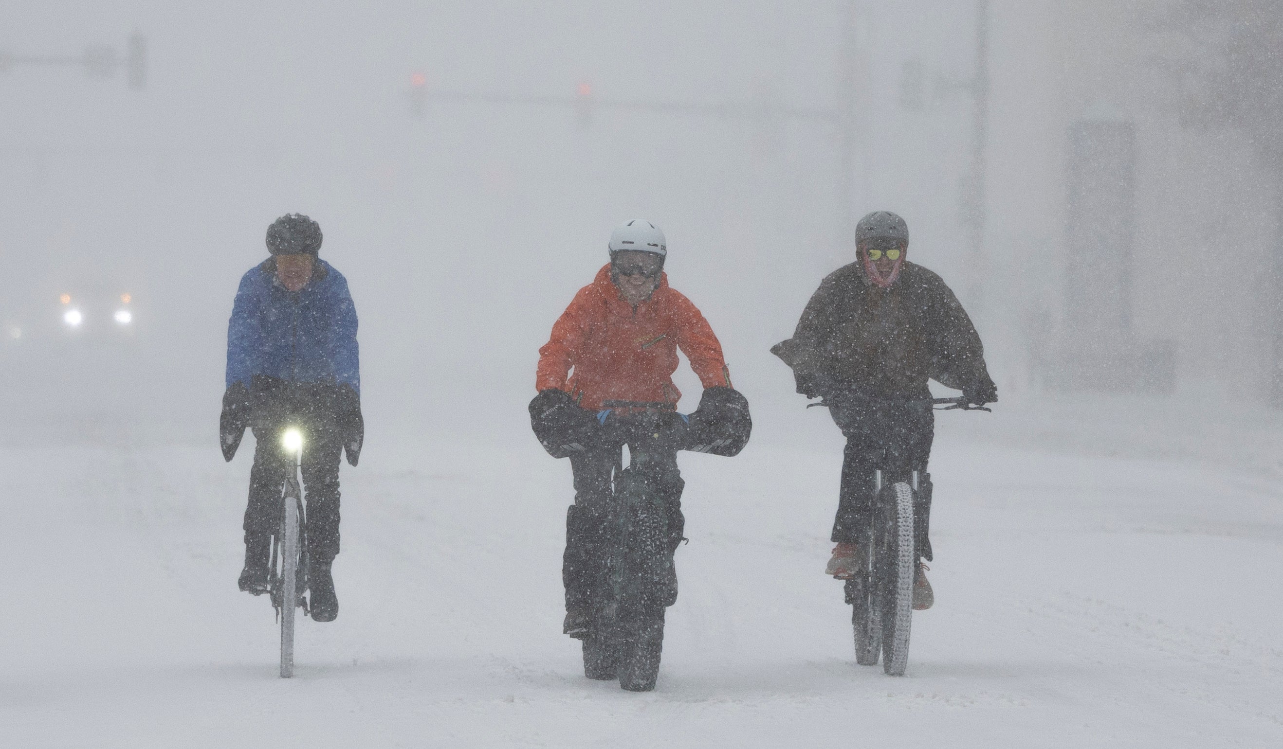 Cyclists travel through Wichita, Kansas during heavy snowfall on Sunday morning