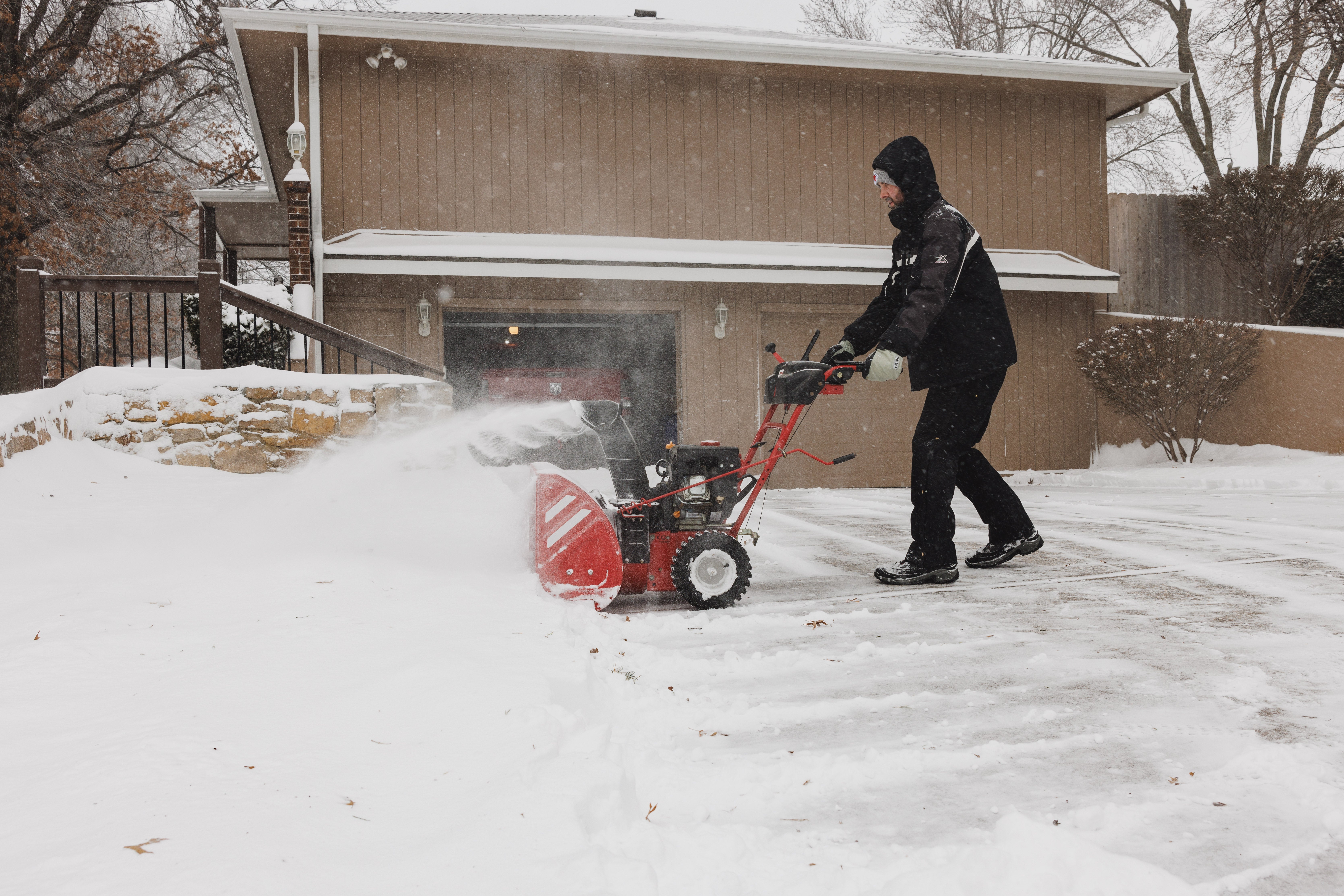 A Shawnee, Kansas resident uses a snow blower amid a major winter storm on Sunday morning