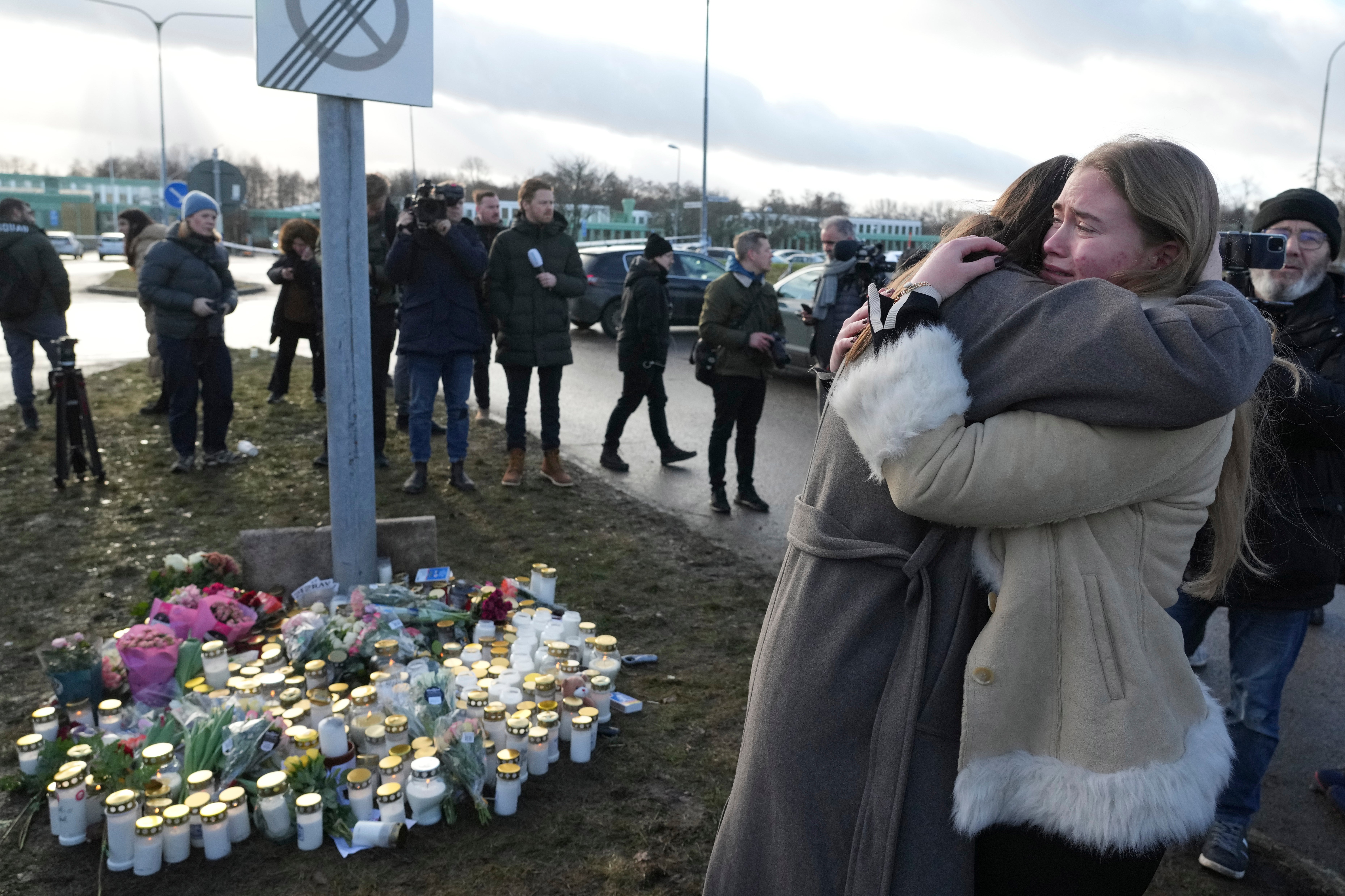 People gather at a makeshift memorial near the scene of a shooting on the outskirts of Orebro, Sweden