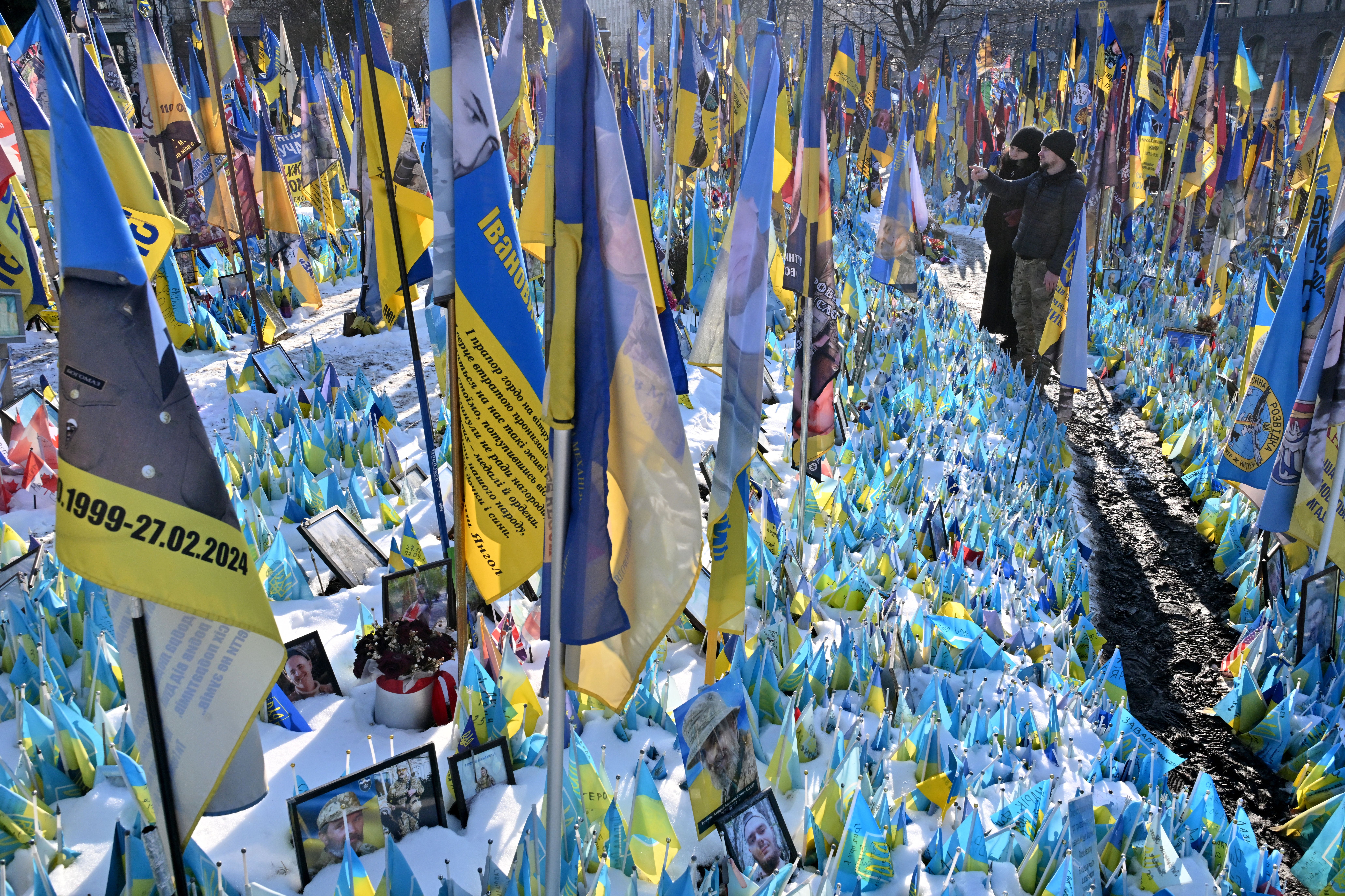 People pay tribute at a makeshift memorial for the fallen Ukrainian and foreign fighters on the Independence Square in Kyiv