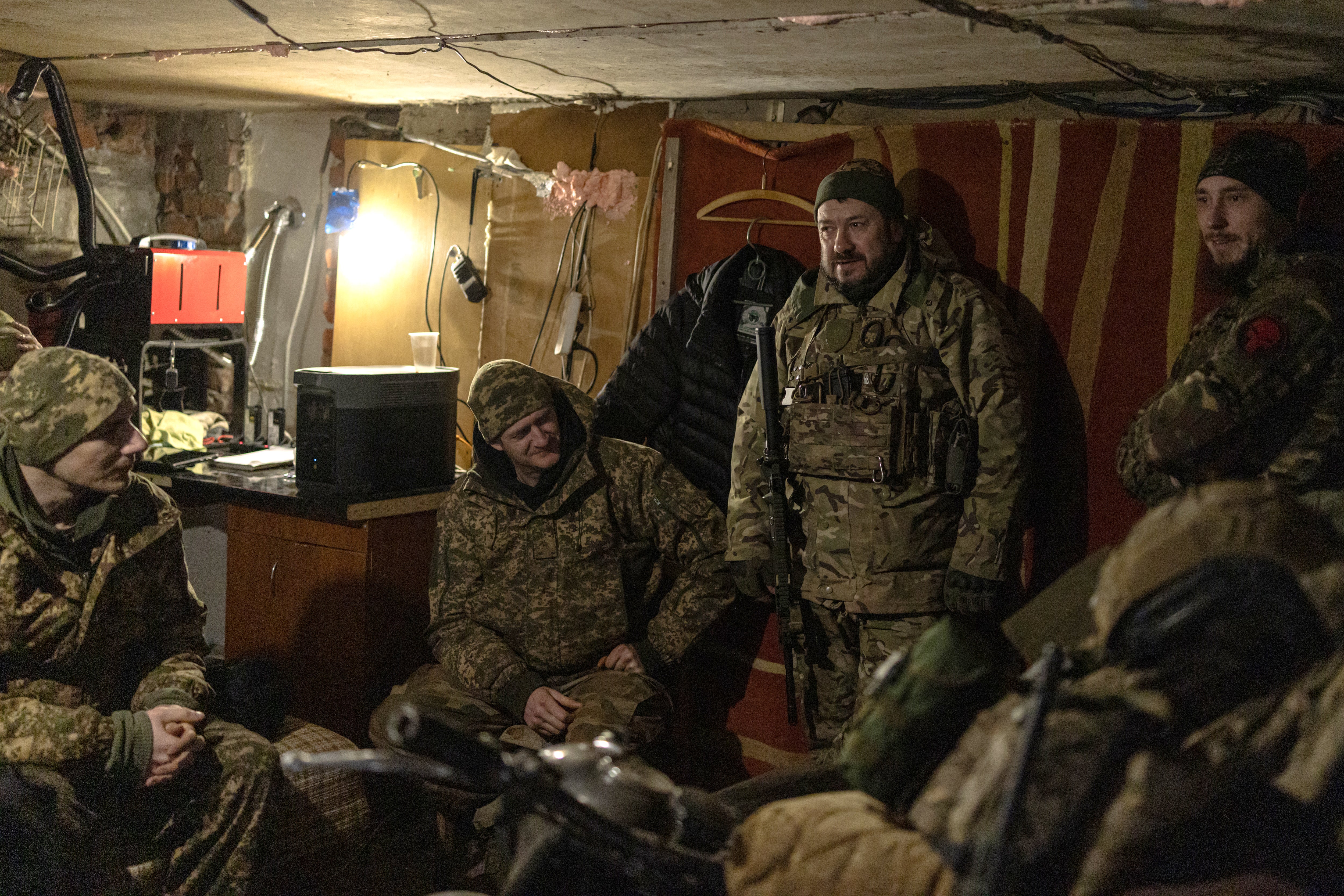 Soldiers wait for coordinates in a garage as they prepare to fire an American-supplied M101 howitzer on Russian combat positions in the Kharkiv region