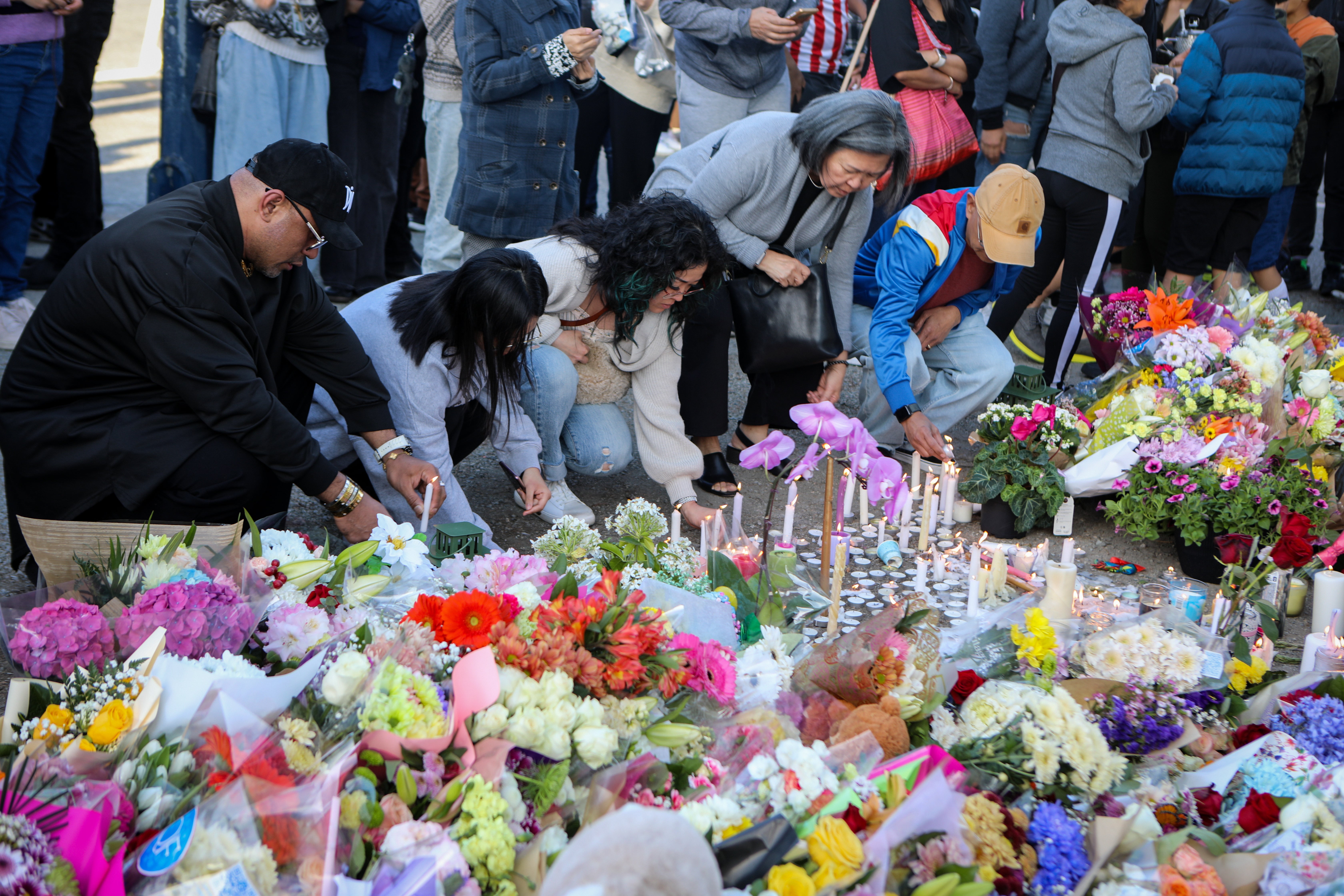 Mourners light candles at a memorial for the victims