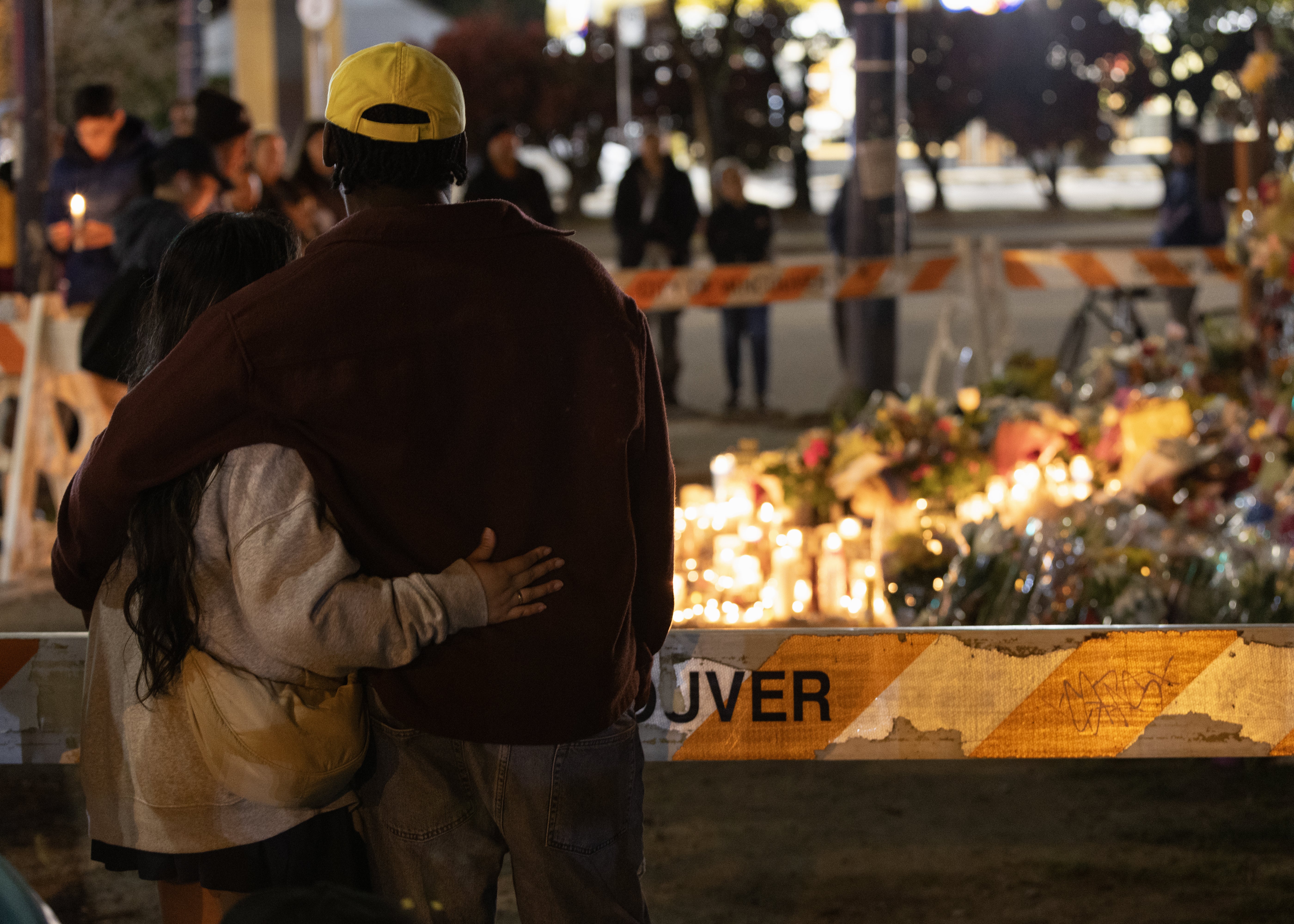 People embrace at the candlelight vigil near the scene where a car drove into a crowd of people during the Lapu Lapu Festival