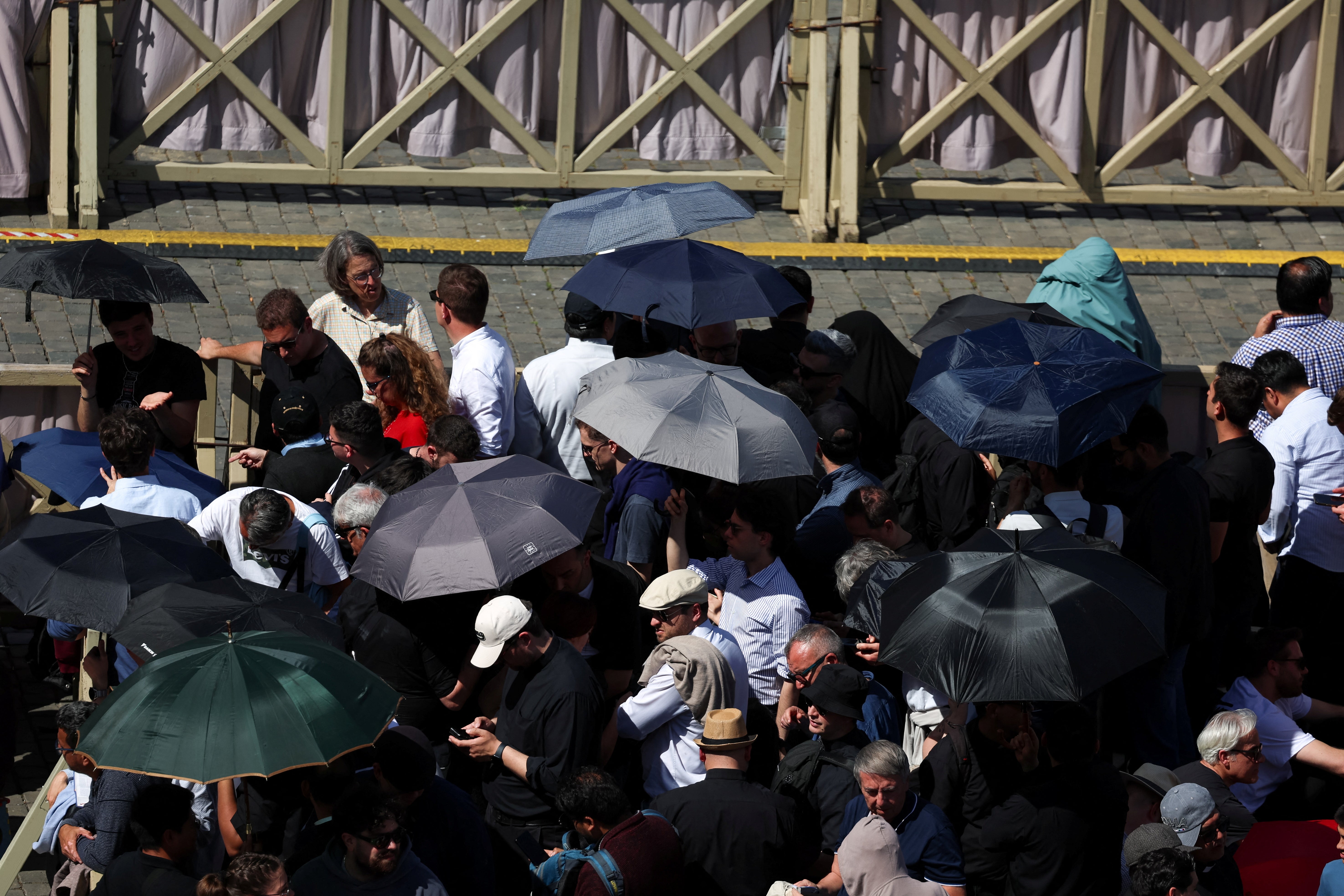 People use umbrellas to shield themselves from the sun in St Peter’s Square